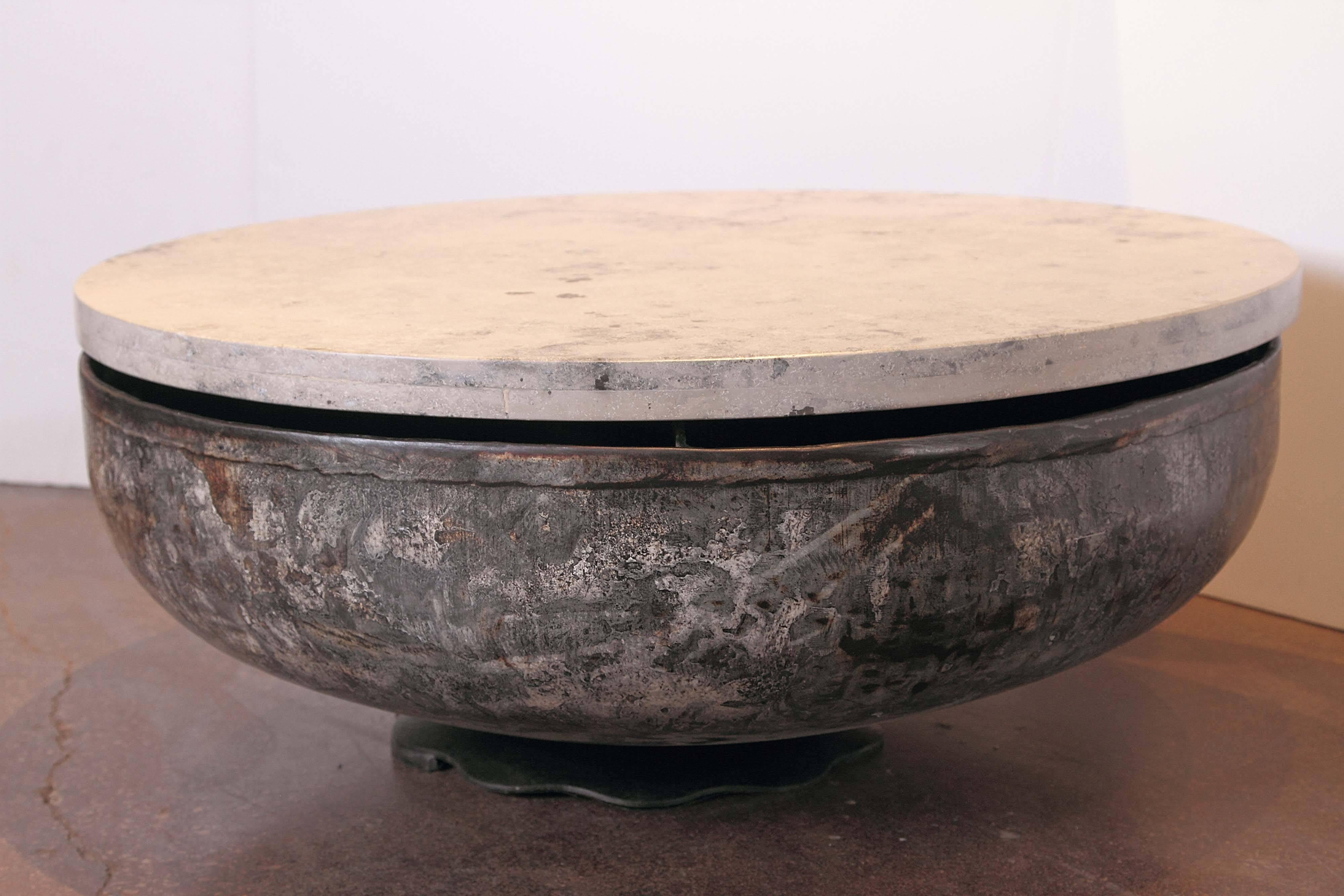 Transitional round low coffee table. 
Spotted patina of grey, gold and crème fill the coloration of the vintage medieval style iron serving dish. 
Polished jura grey limestone marble-top with 
