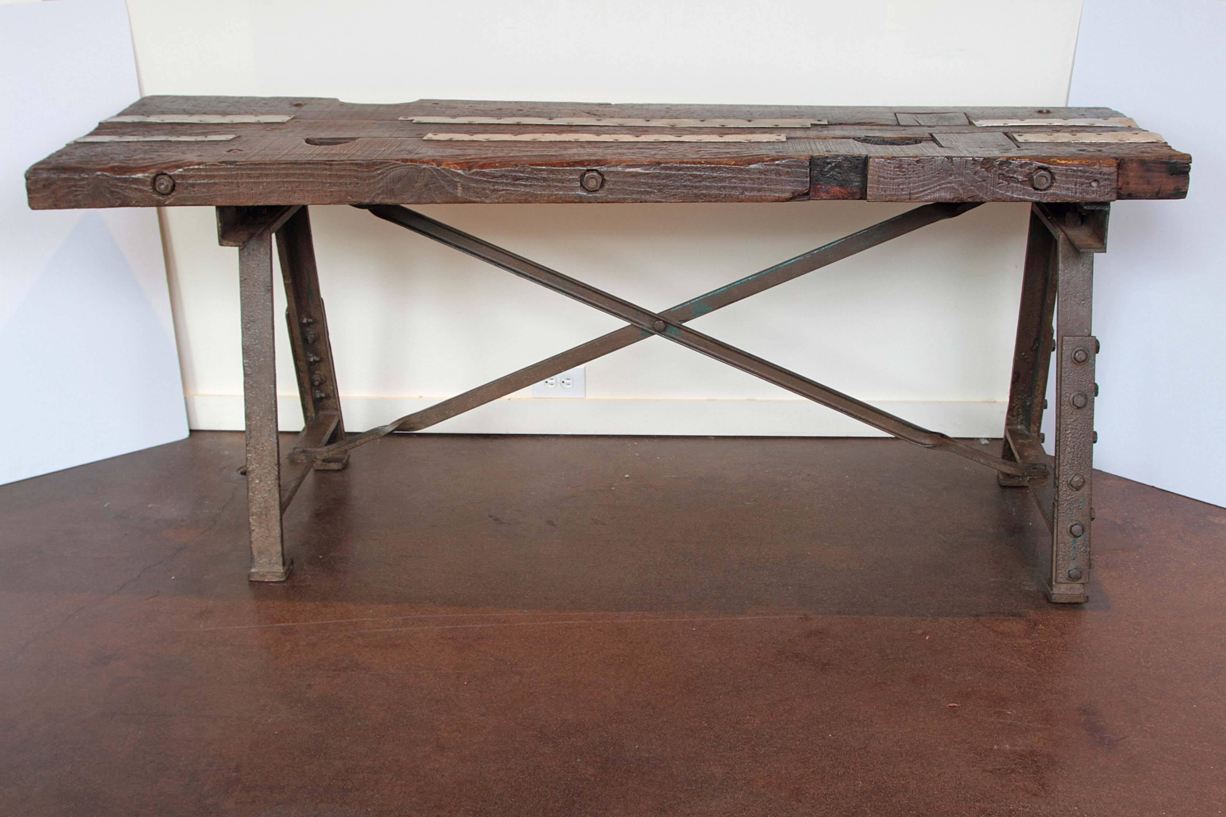 Masculine Industrial Console Table.
Antique French work table from Roubaix area. 
Belonged to a tradesmen's workshop 1920, France.
Original patina of patinated steel base with cast iron bolts. 
Narrow sheets of metal lay up top of walnut wood