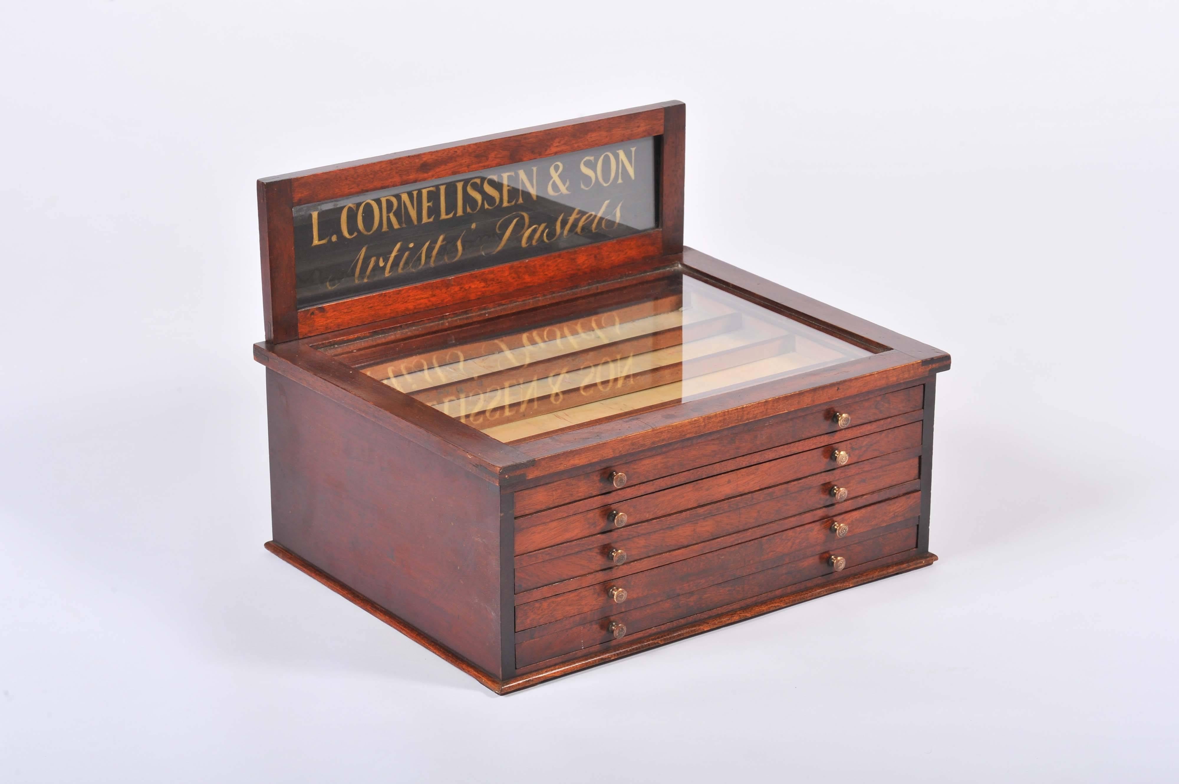 A beautiful antique wooden artist's pastels display cabinet ascribed to the renowned Victorian artist supply shop L. Cornelissen & Son, London. 

The cabinet contains five drawers, with each drawer divided into Sub-compartments, along with a glass