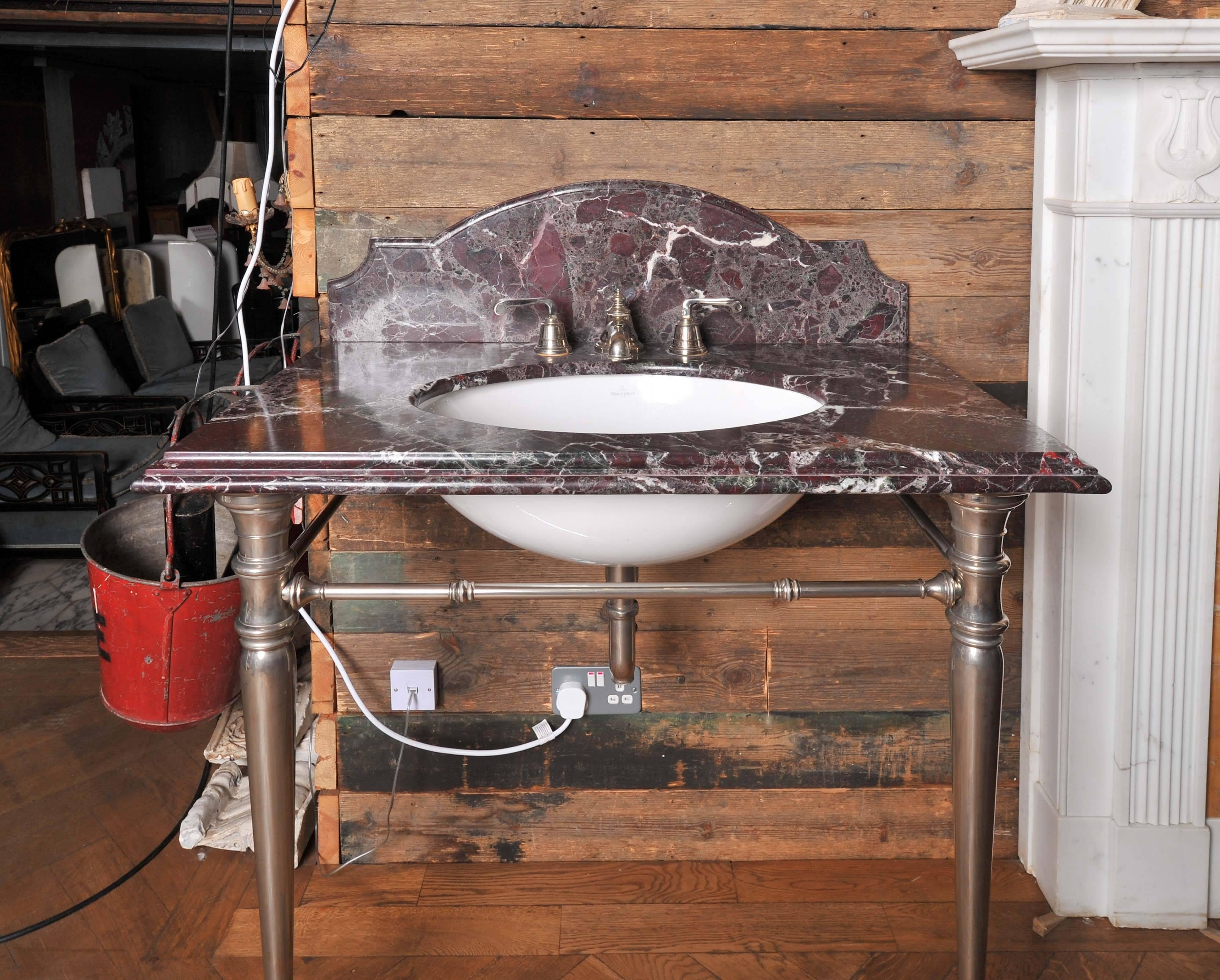An antique style washstand sink with a richly veined dark marble surface and shaped splash back and elegantly tapering nickel legs. The vintage washstand sink has matching nickel taps in an antique style.

 