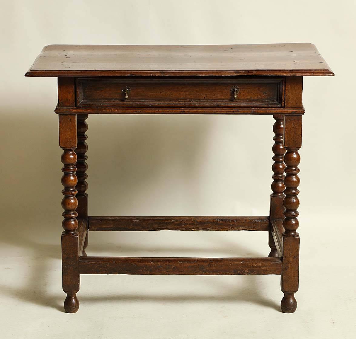 Good English late 17th century oak side table, the molded two plank top over single molded front drawer, standing on bobbin and reel turned legs joined by box stretcher and standing on original turned feet.

Measures: .29.75