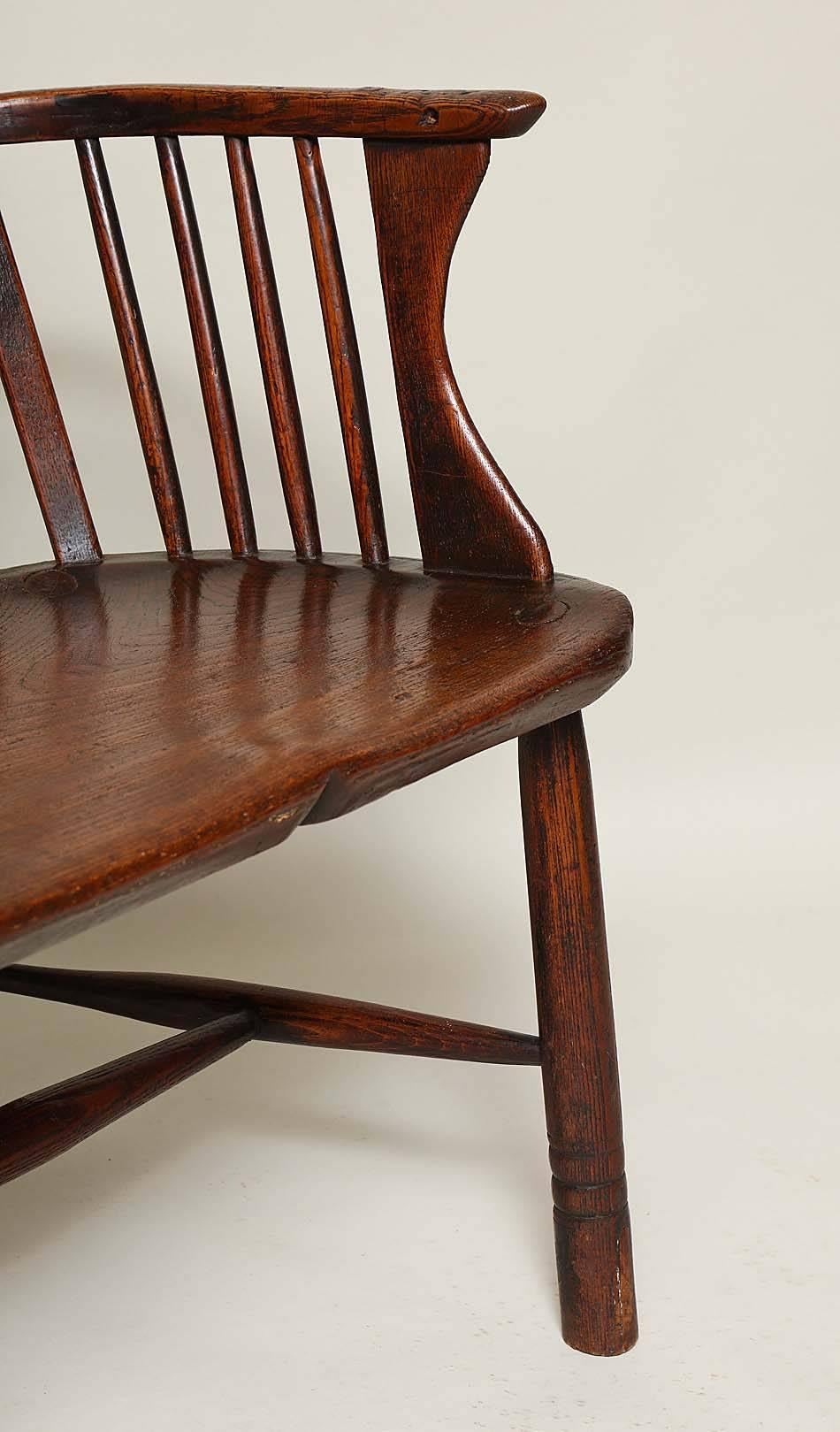 Fine 18th century English comb back windsor armchair, having richly shaped crest over spindle and vasiform splat, the arm with shaped solid supports, standing on ring turned pole legs joined by 