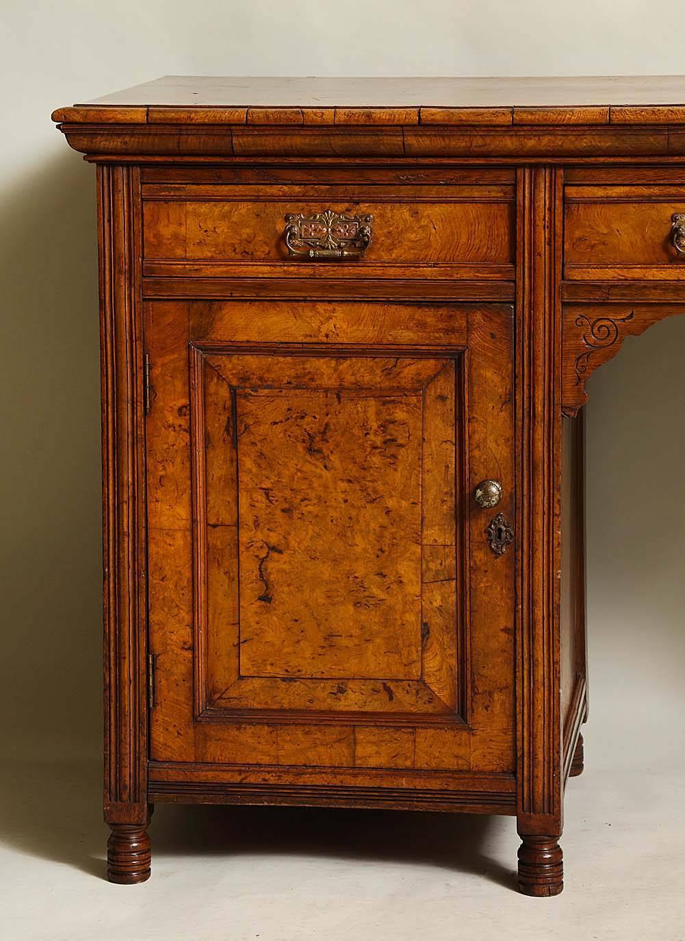 Richly patinated late 19th century English burl wood serving cabinet, the highly figured and bookmatched top with thumb molded edge over three drawers retaining their elaborate mixed metal handles, over shaped and scratch carved apron, flanked by