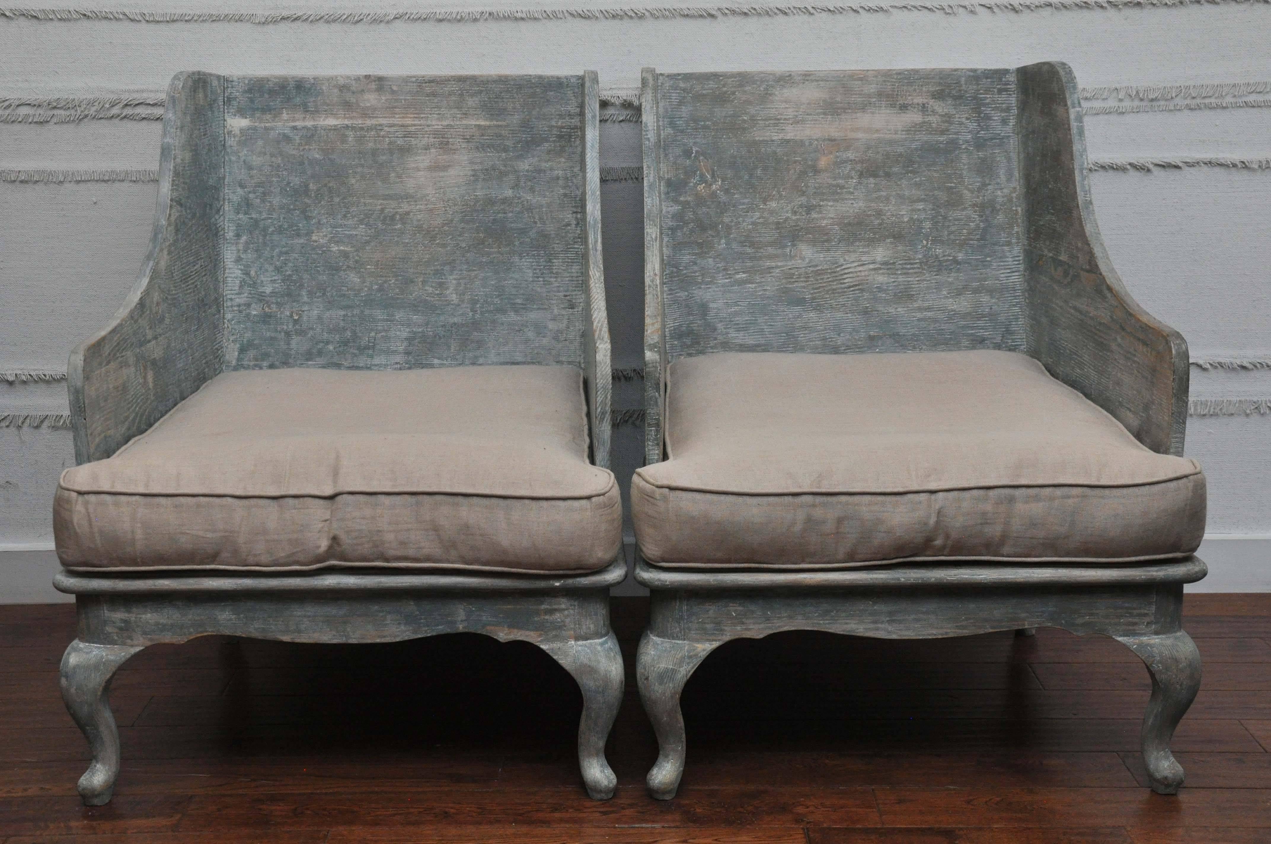 Early 20th century reproduction pair of primitive painted wood chairs. Found in France. Weathered/distressed blue-green painted finish with natural colored linen cushions.

Dimensions: 
Seat depth: 29