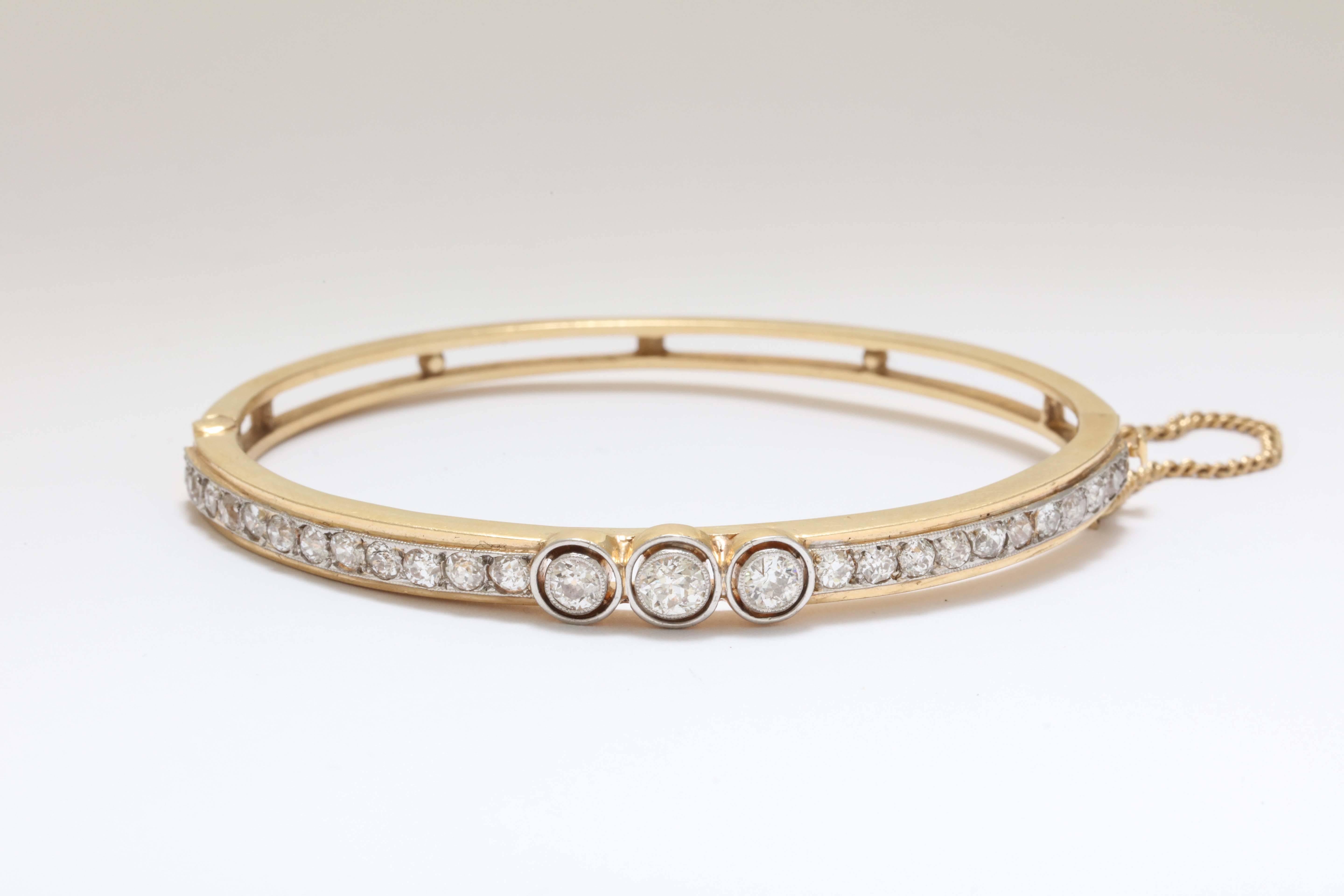 A elegant 14-karat gold oval bangle bracelet with European bezel set diamonds.