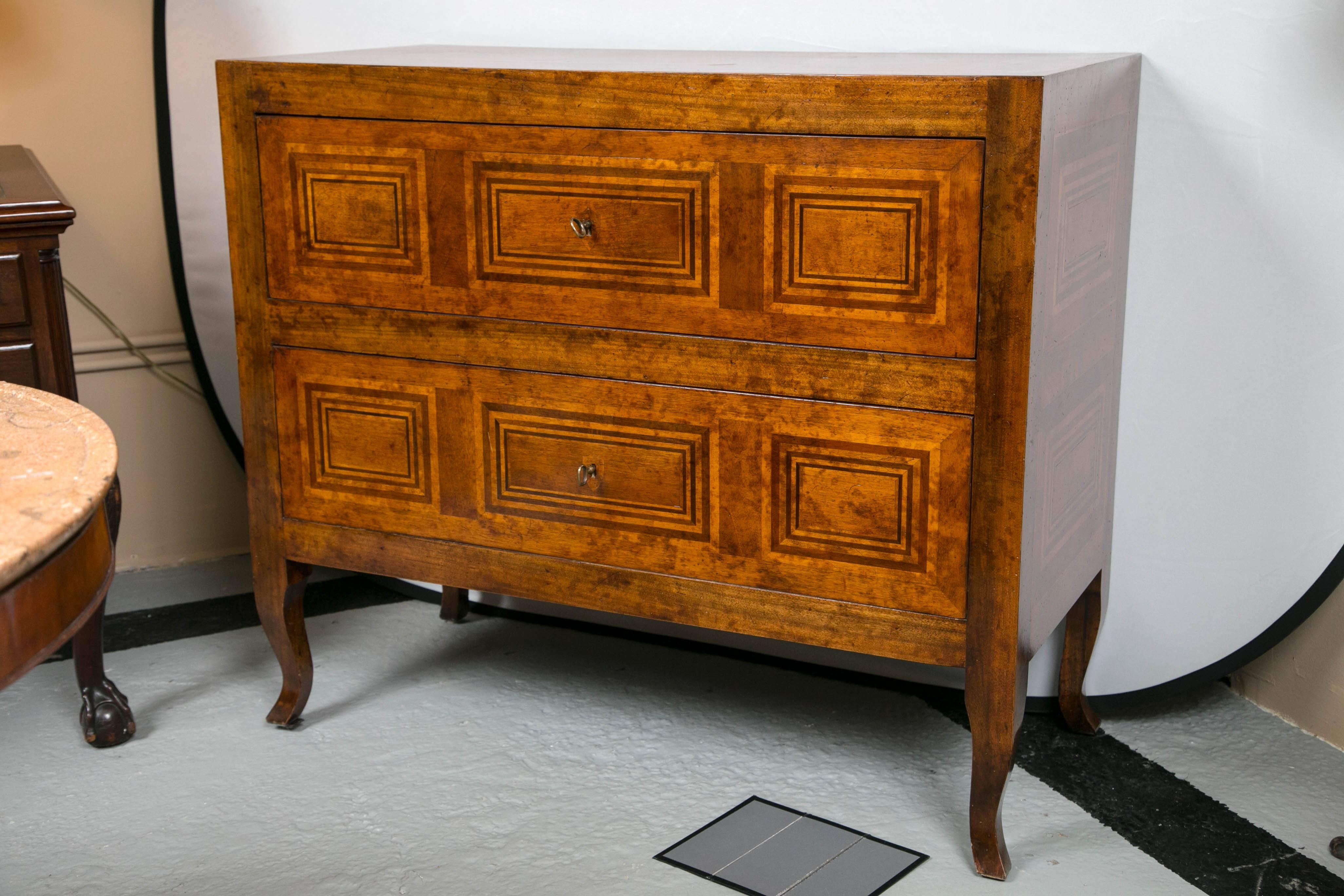 A two-drawer Italian handmade inlaid Continental style commode. Fine quality vintage commode with geometric design inlays on the front, sides and top. Having all the old world charm one would like in a continental commode. Fine to sit on its own or