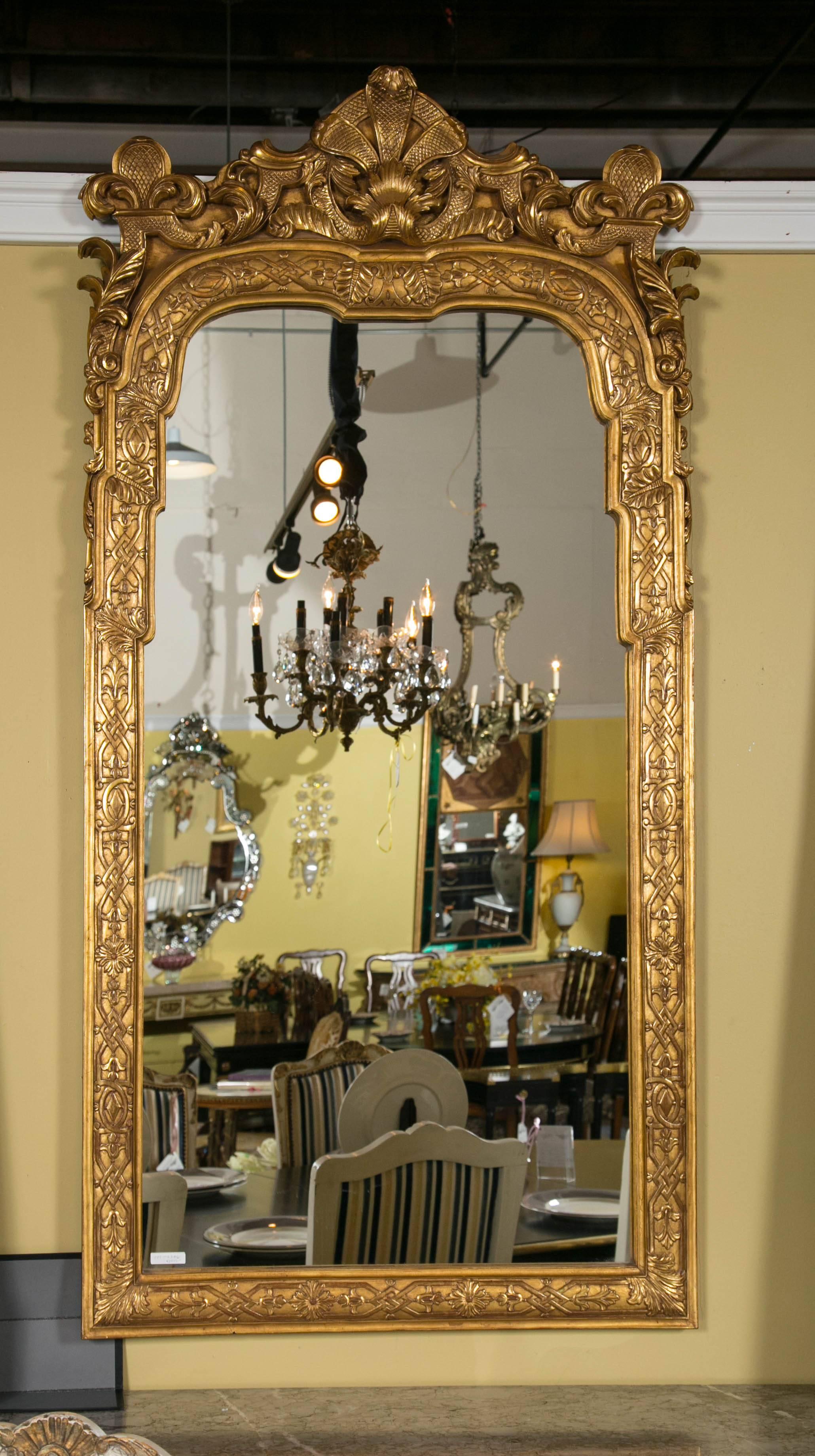 A solid gilt wooden wall or console mirror. The rectangular solid wooden frame having carved roses, leafs and vine design in a fine clay under gilt finish. This Louis XV style frame would look beautiful in any area over any console or sideboard.