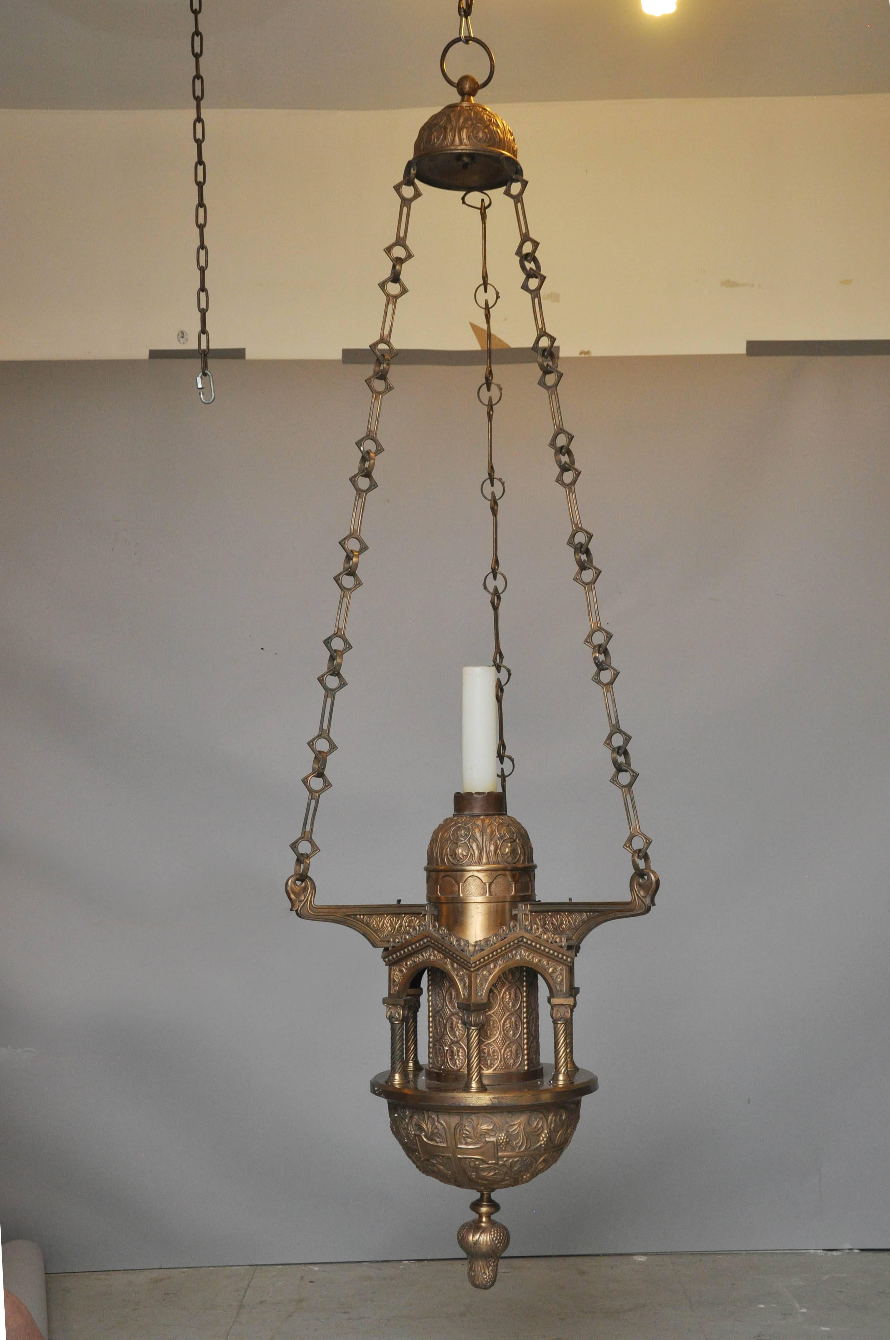 Large one-of-a-kind cathedral  renaissance style bronze and repoussé candle chandelier in the manner of E.F Caldwell, from the 1920's. Three bronze chain links with circular and diamond shapes suspended from a bronze repoussé canopy. Middle bronze