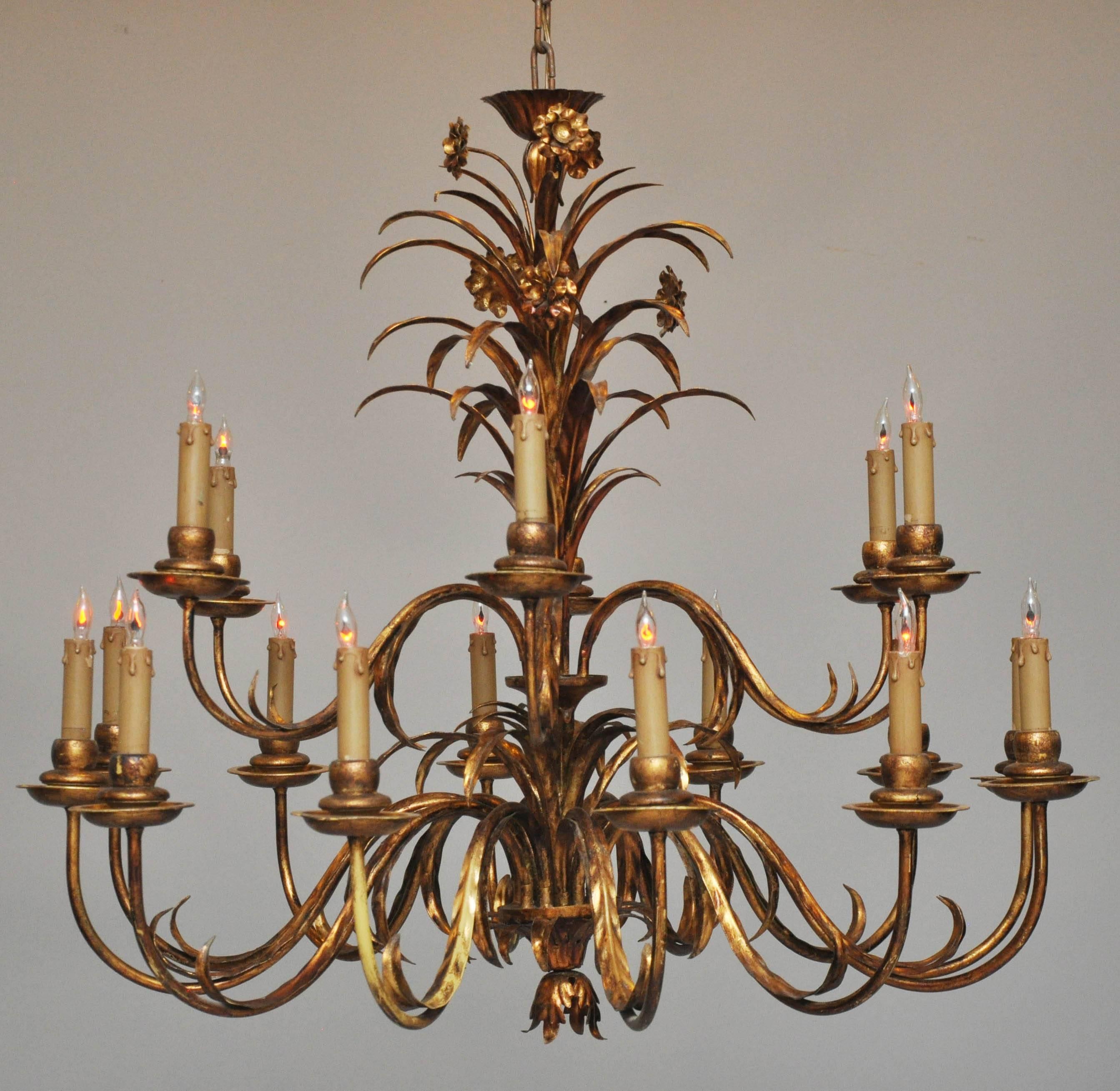 Oversized Italian two-tiered 18 light tole chandelier with aged gilt finish. scrolled arms in the shape of a singular speared leaf ending in a candle light bulb, supported by a central support in the form of spray of long speared leaves and flower