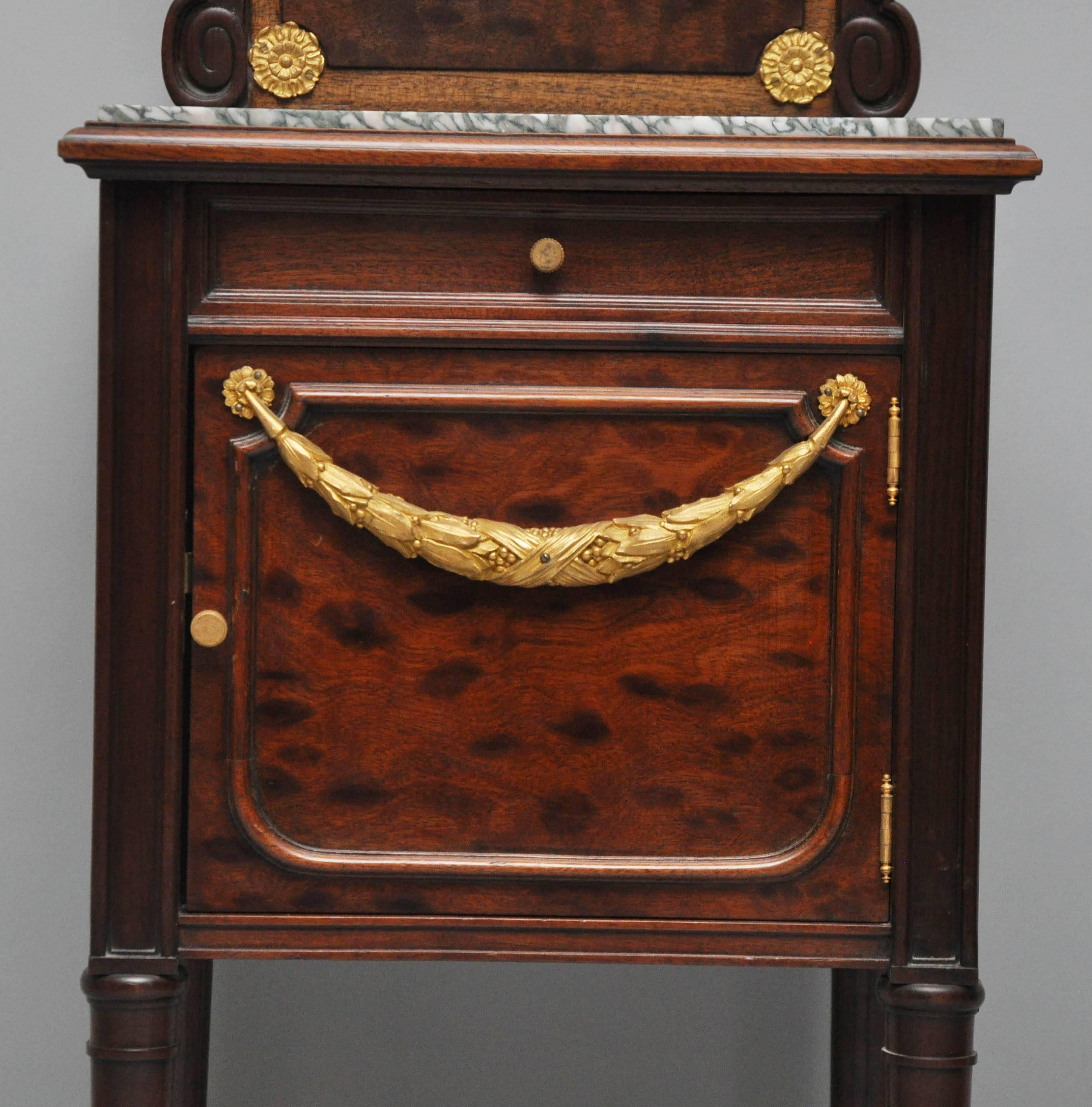 French burl mahogany bedside table, square marble top surface above frieze drawer and paneled cabinet with gilt mercury bronze draped garland revealing original porcelain interior originally used for chamber pot, supported on four circular tapered