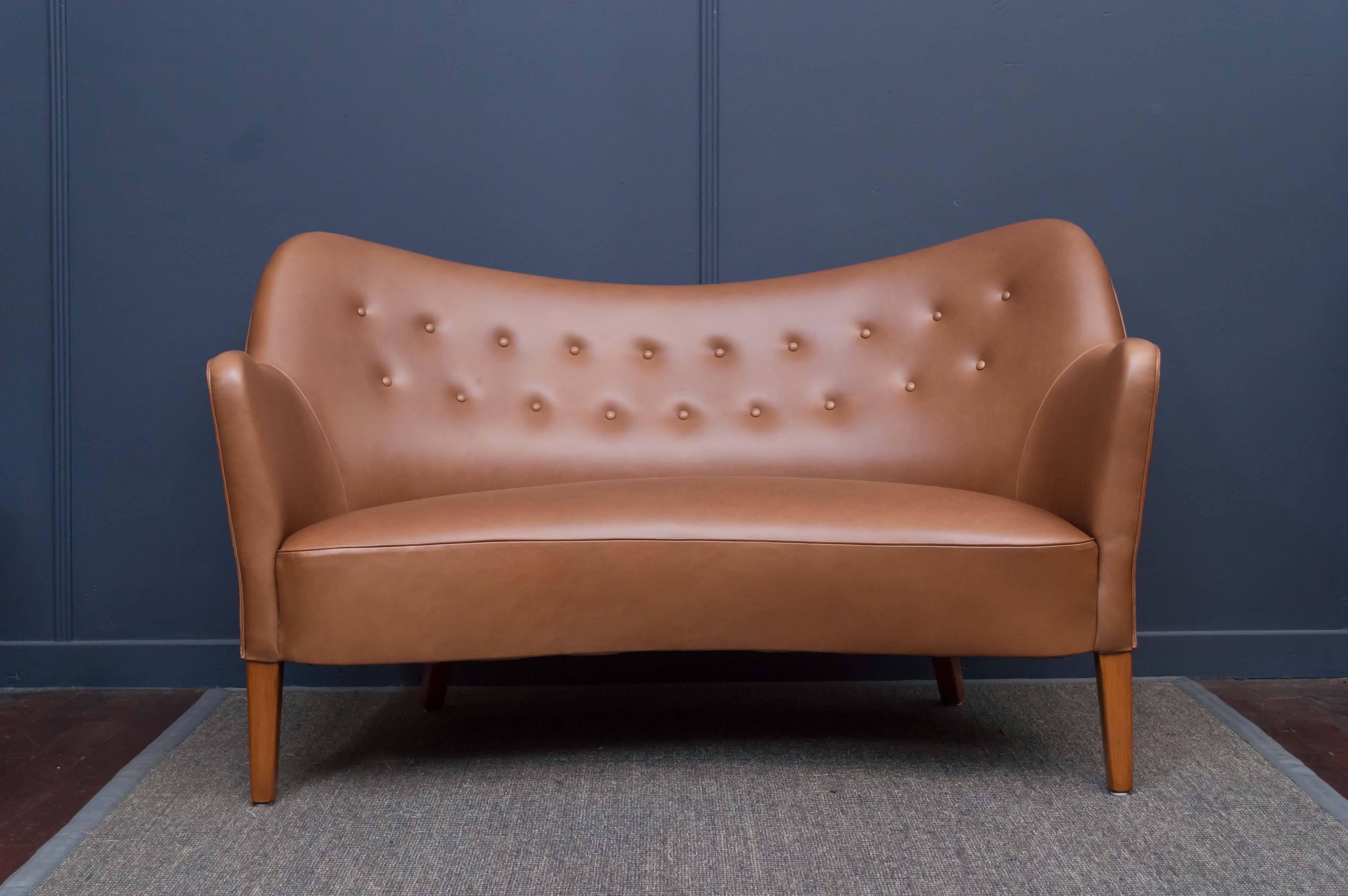 Fluid and inviting petite sofa made by Slagelse Mobelvaerk, Denmark.
High quality solid construction teak frame, newly upholstered in cognac leather.