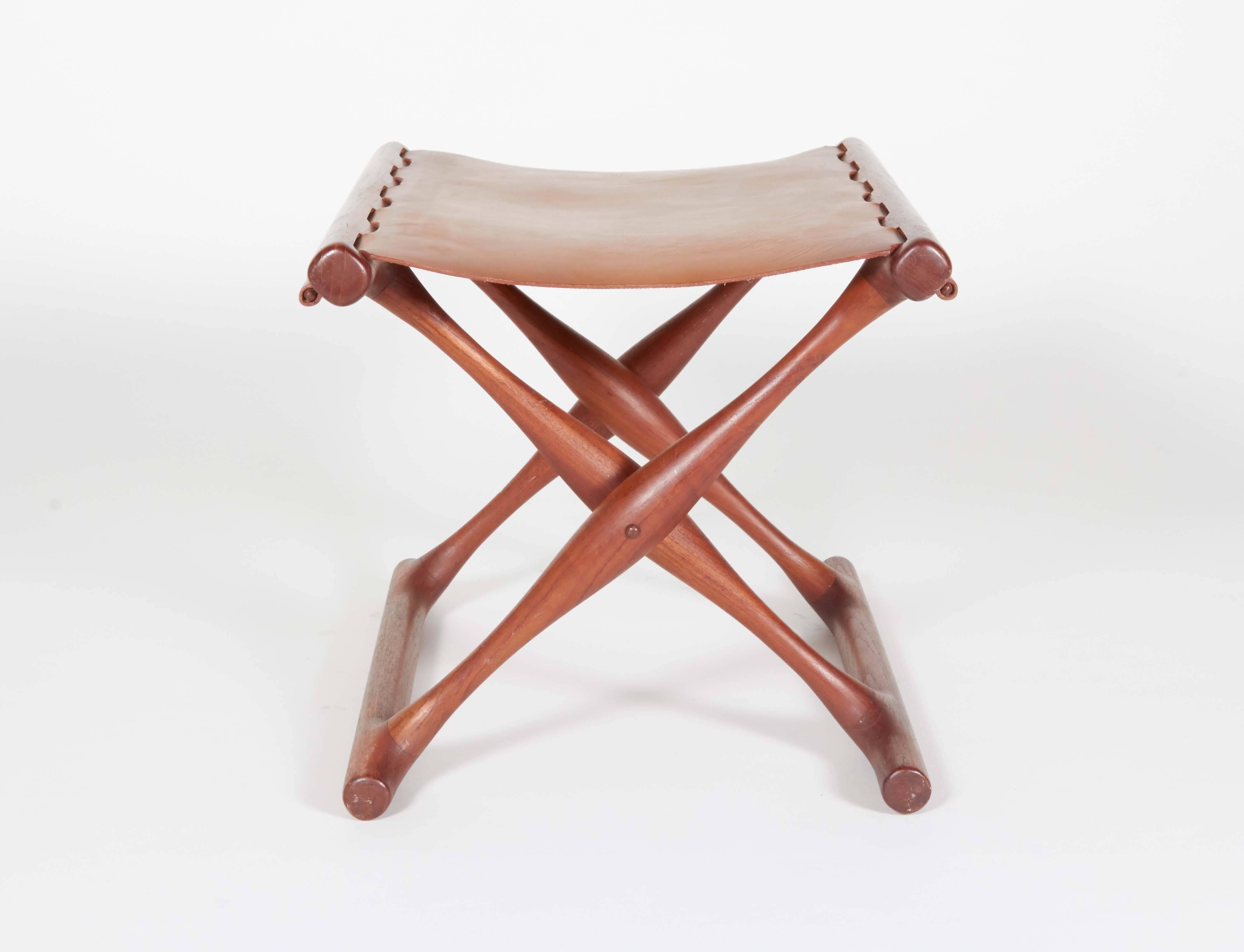 This sculptural folding stool is brilliantly constructed with wooden pins securing the original leather seat.