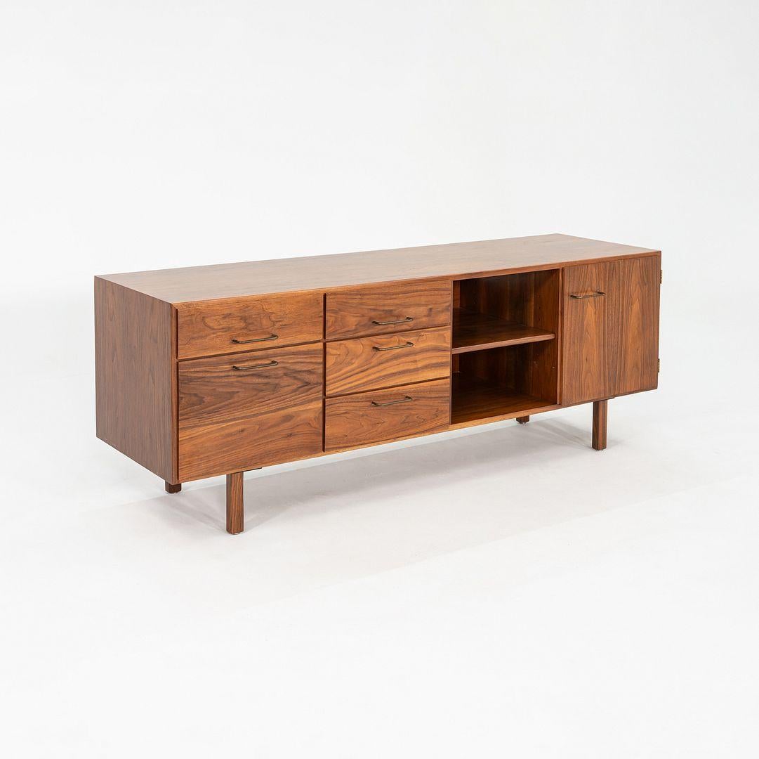 This is a walnut credenza / cabinet designed by Jens Risom and produced by his company, Jens Risom Design. This particular piece was handcrafted in the USA and dates back to the 1970s. The credenza has a beautifully grained walnut case, with several