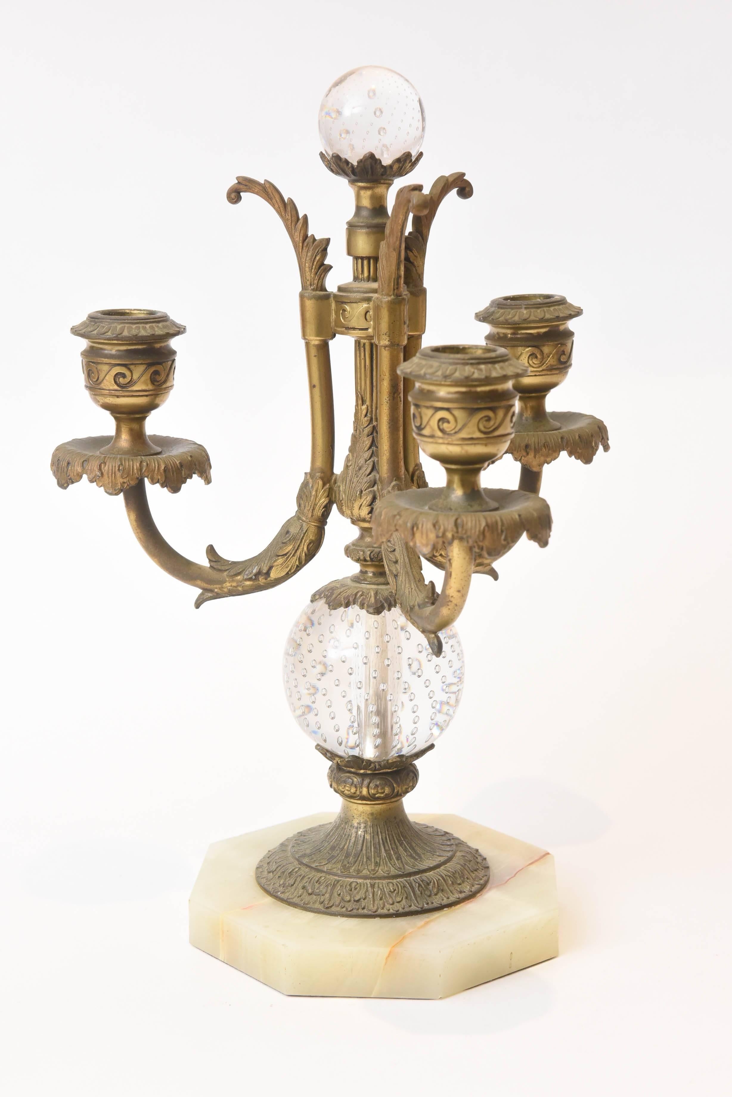 A wonderful and impressive three-piece set from Pairpoint during a period of their greatest success. A hand chased gilt metal candelabra main center piece with three arms, two controlled glass bubble accents and faux marble base. The matching pair