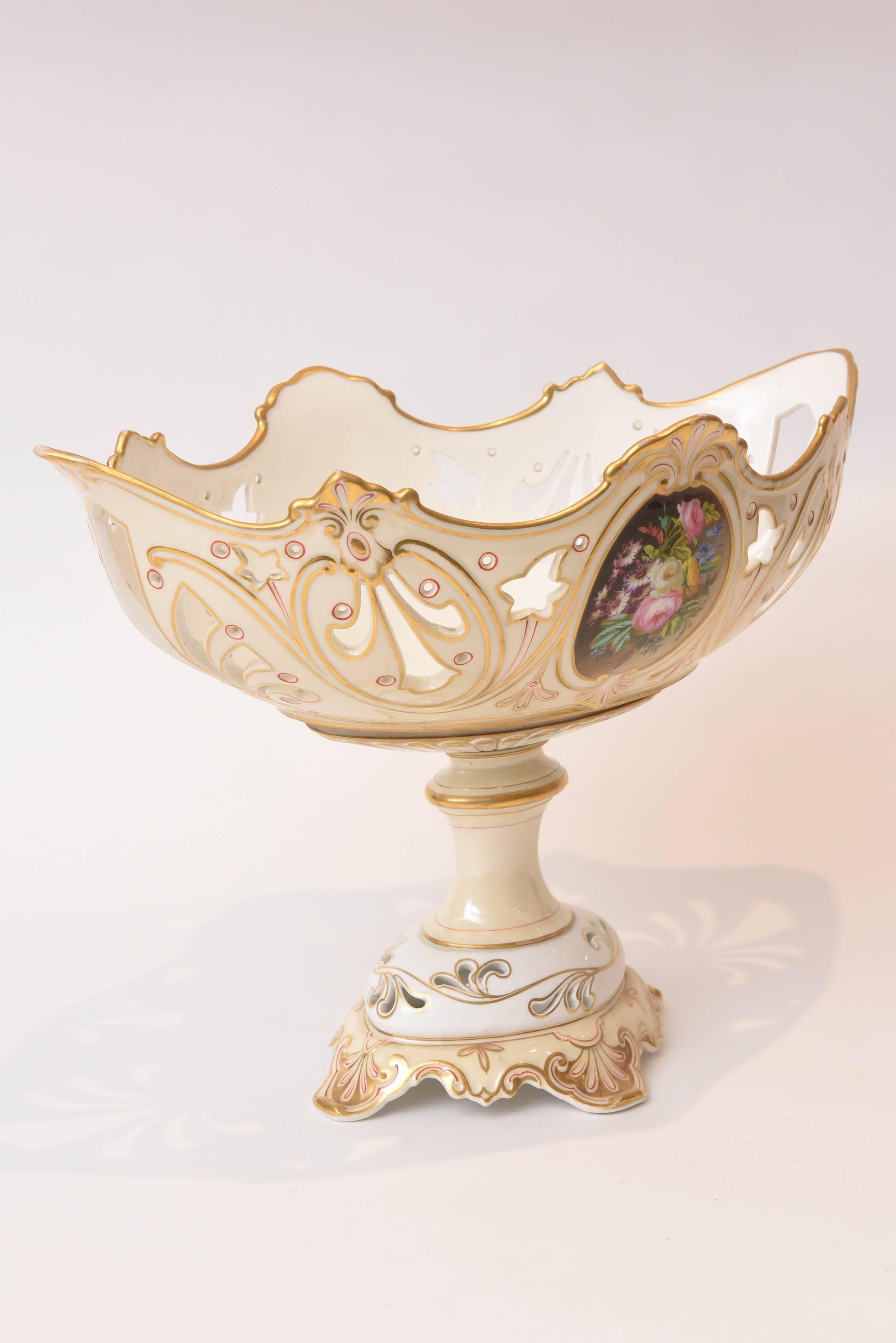 A stunning piece of Old Paris porcelain that features two sides of beautiful hand-painted floral panels, hand-cut work and hand-painted trim. Nicely shaped with a long and deep boat shaped bowl and a nice tall pedestal base. While we find no