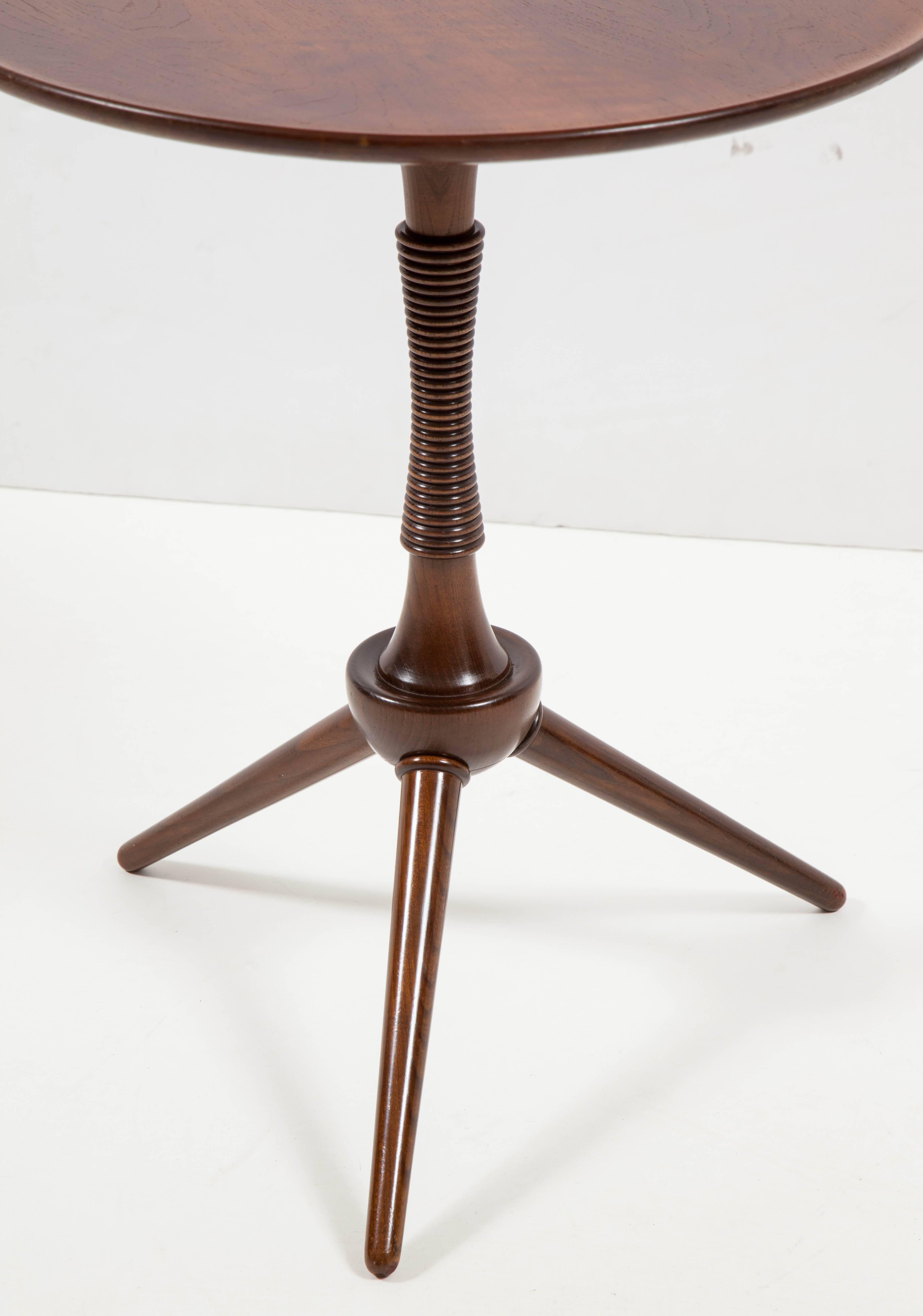 A Danish mahogany tripod table, circa 1940s, designed and produced by Frits Henningsen, with a circular lipped top raised on a partially spool turned tapered and spreading stem ending with three circular tapered legs.