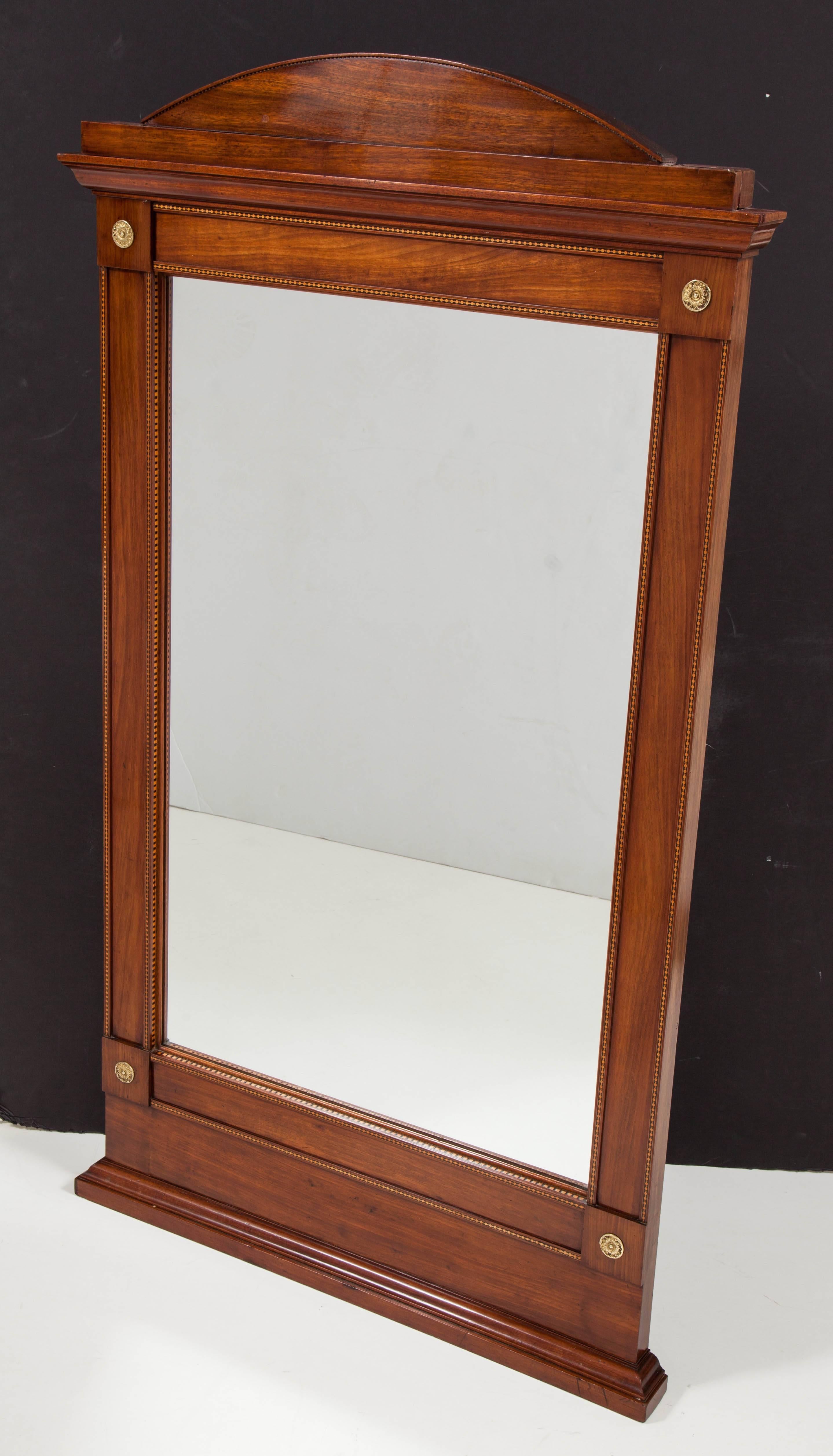 A Swedish Empire mahogany mirror with subtle fruitwood geometric inlays, circa 1820, with an arched top above a steeped molding, the replaced mirror plate surrounded by a flat and molded rectangular frame with box corners mounted with bronze