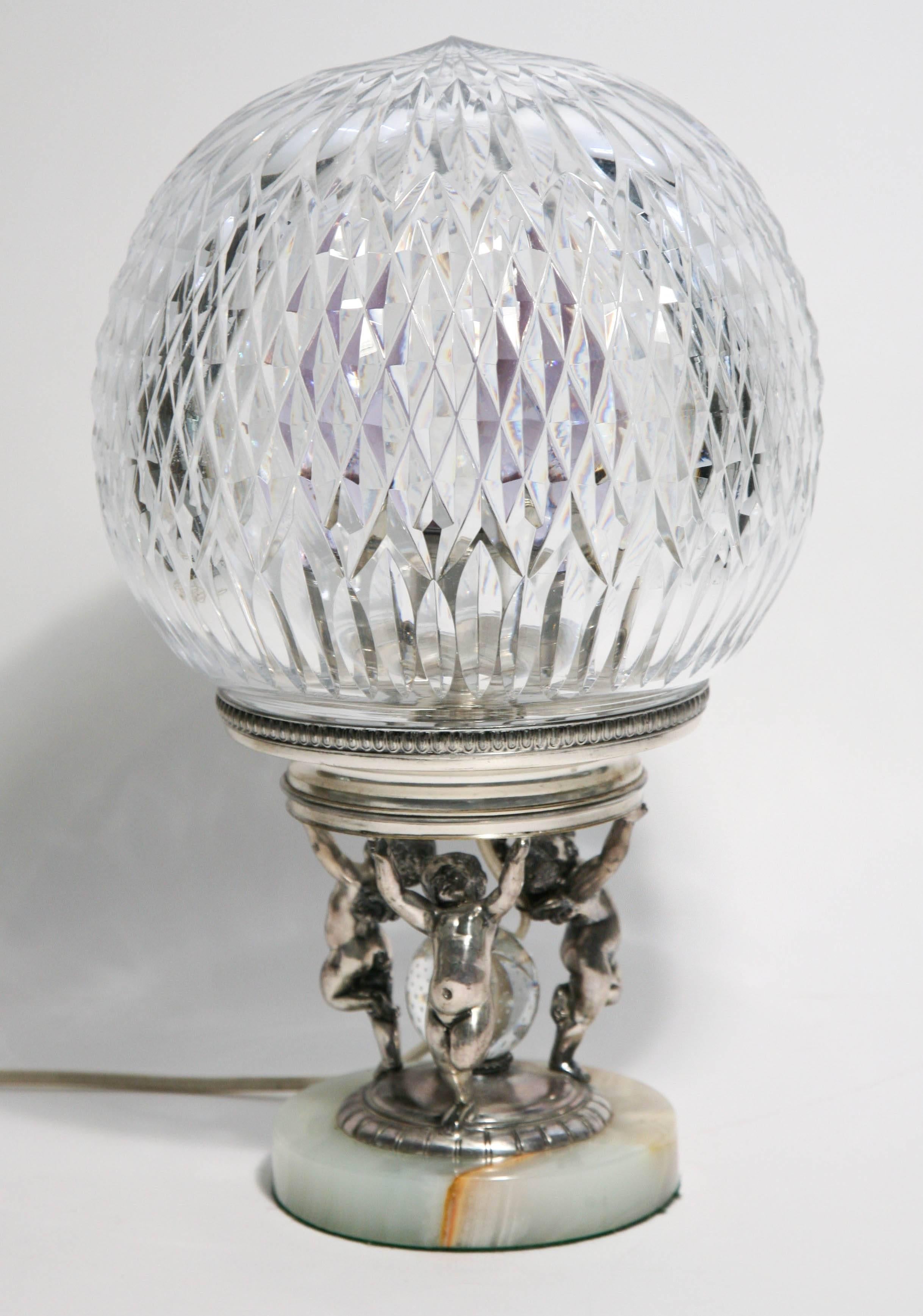 A rare and hard to find all original piece by one of America's storied cut glass and metalwork’s firm of Pairpoint, New Bedford MA. A fully cut crystal globe rests on a hand crafted silver plated base of three figural ptti supporting their treasure.