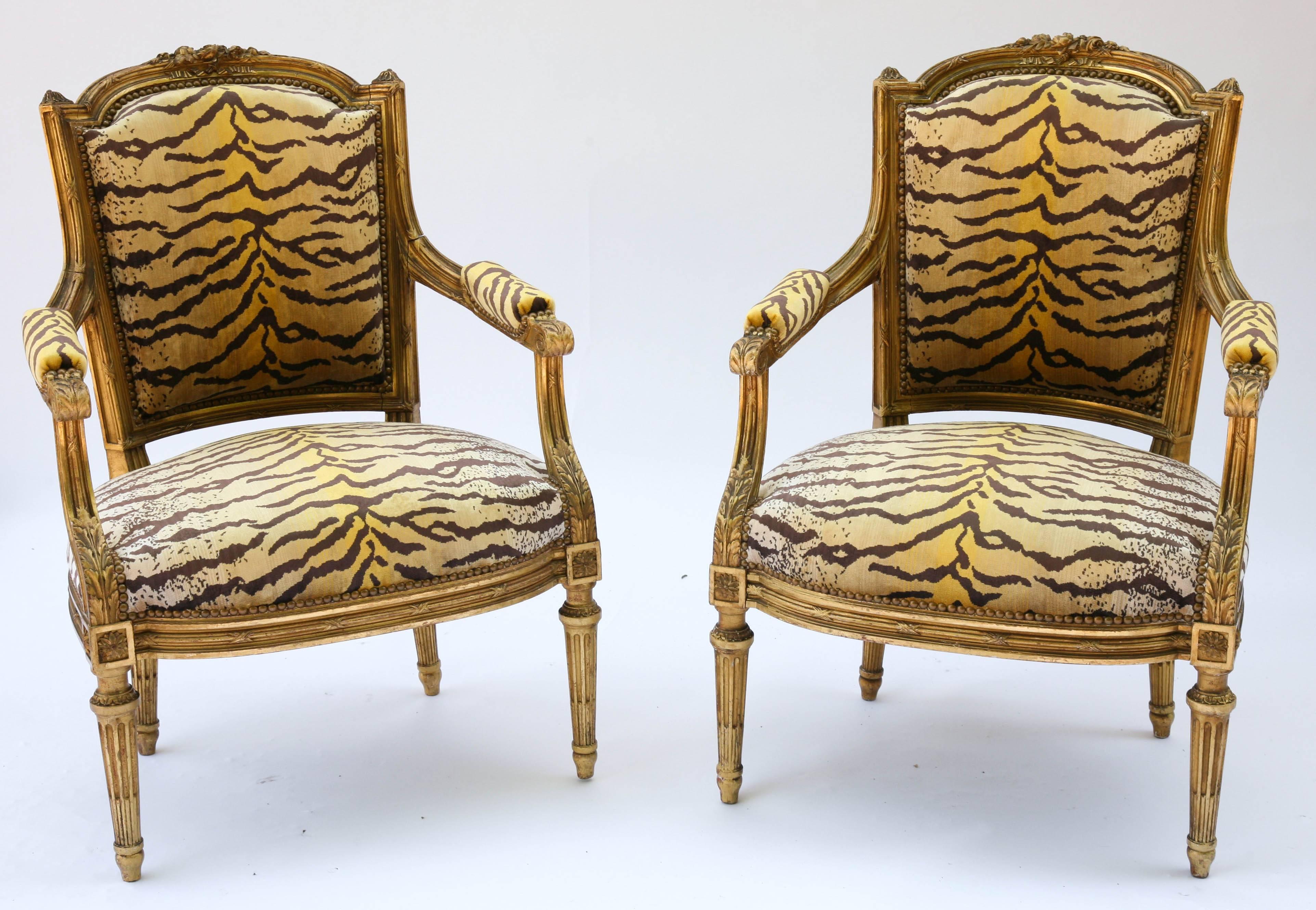 Exquisite pair of signed "Guignon & Fils," Louis XVI fauteuils, of carved giltwood, each having an arched channeled crestrail, centered by flowers and ribbons, flanked by finials, padded tapering back into seat with crown cushion,