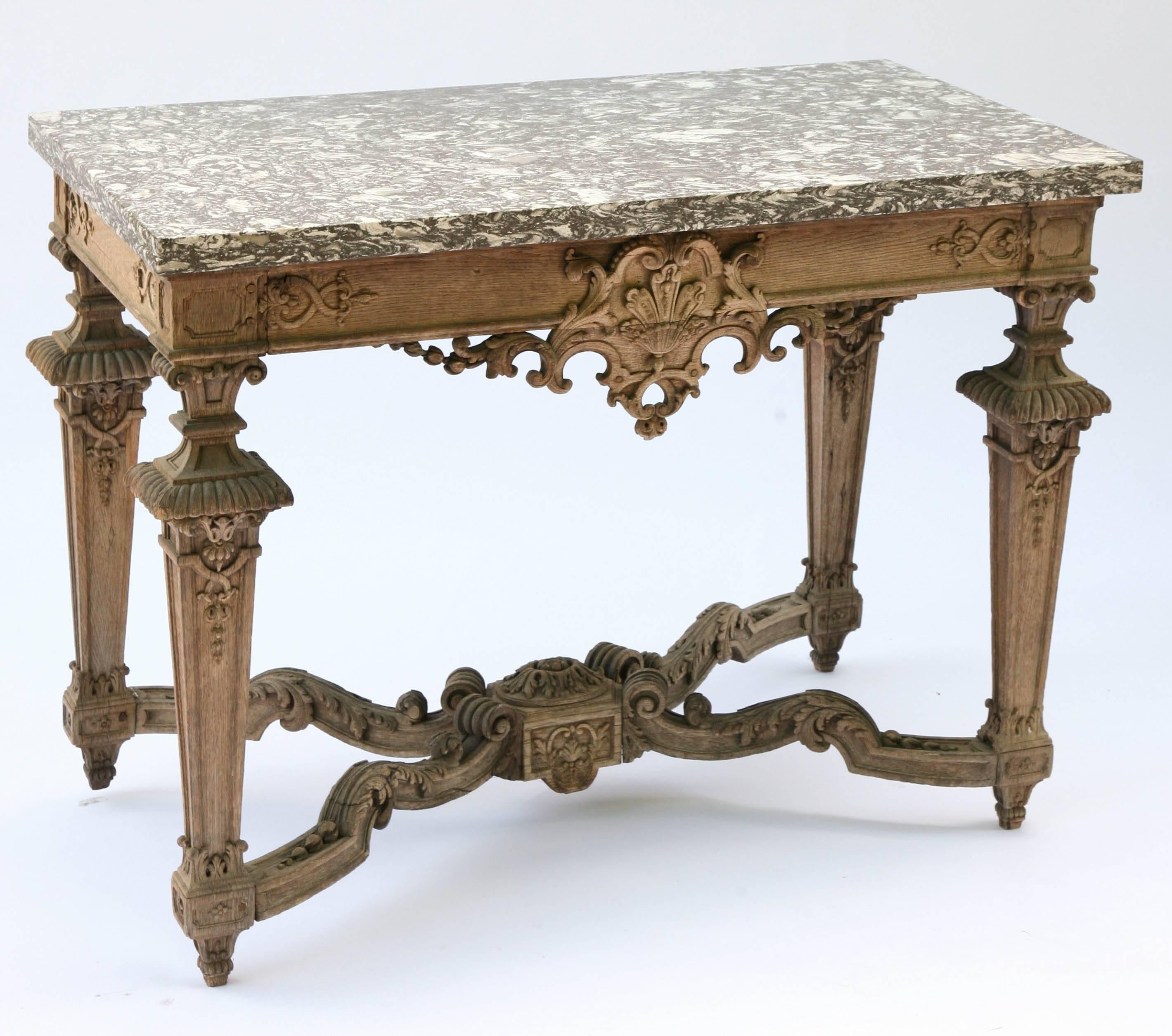 Console table, having a rectangular top of black marble, on elaborately carved bleached oak base, its apron outcarved and draped with scrolling flourishes, raised on square tapering legs connected by X-stretcher.

Stock ID: D6575