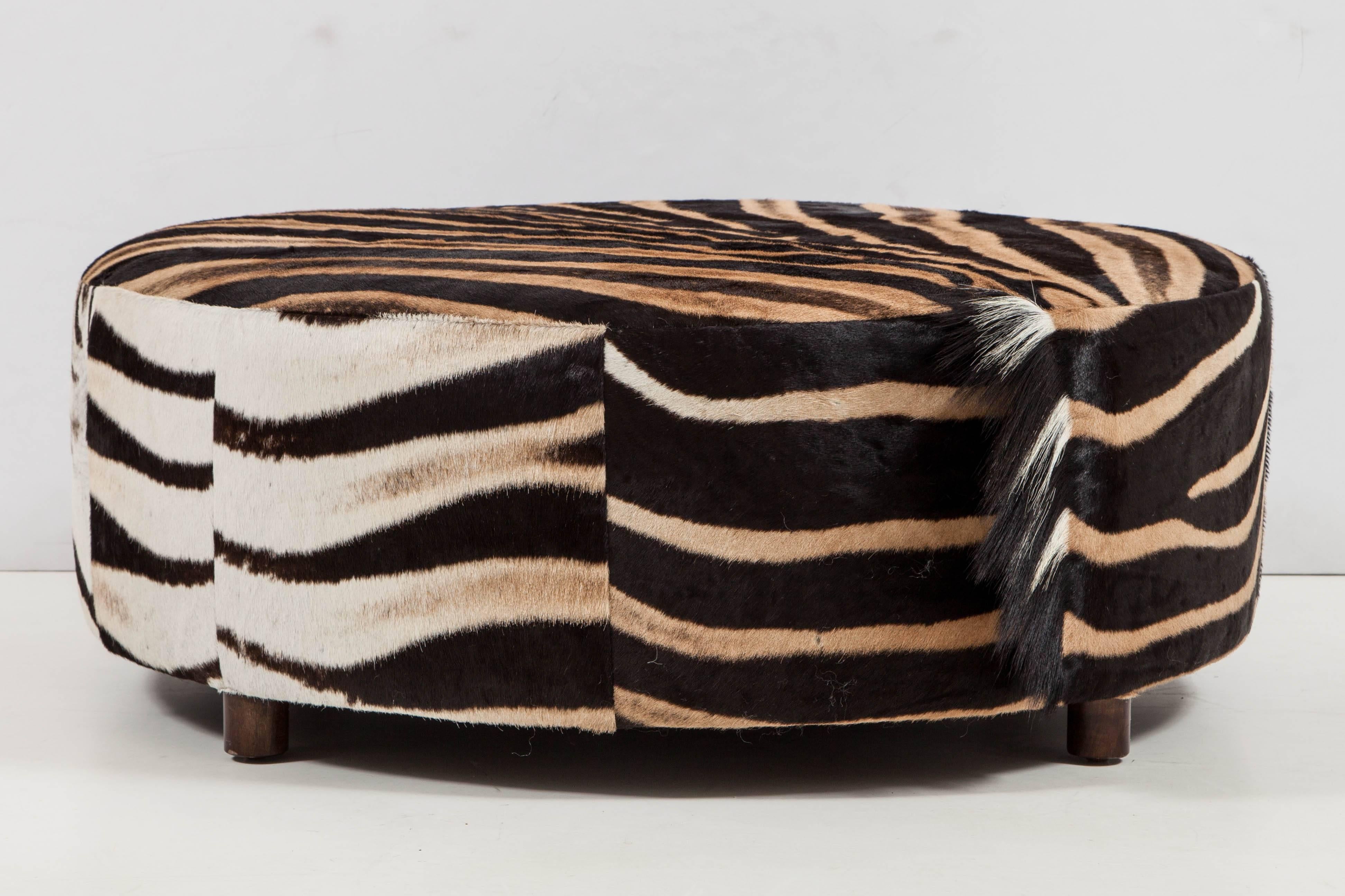 Decorative round zebra ottoman. Wood legs. Measures: Diameter is 36 inches and height is 12 inches. This ottoman is sold but we have one more. Let us know and we will email pictures of the new zebra ottoman.