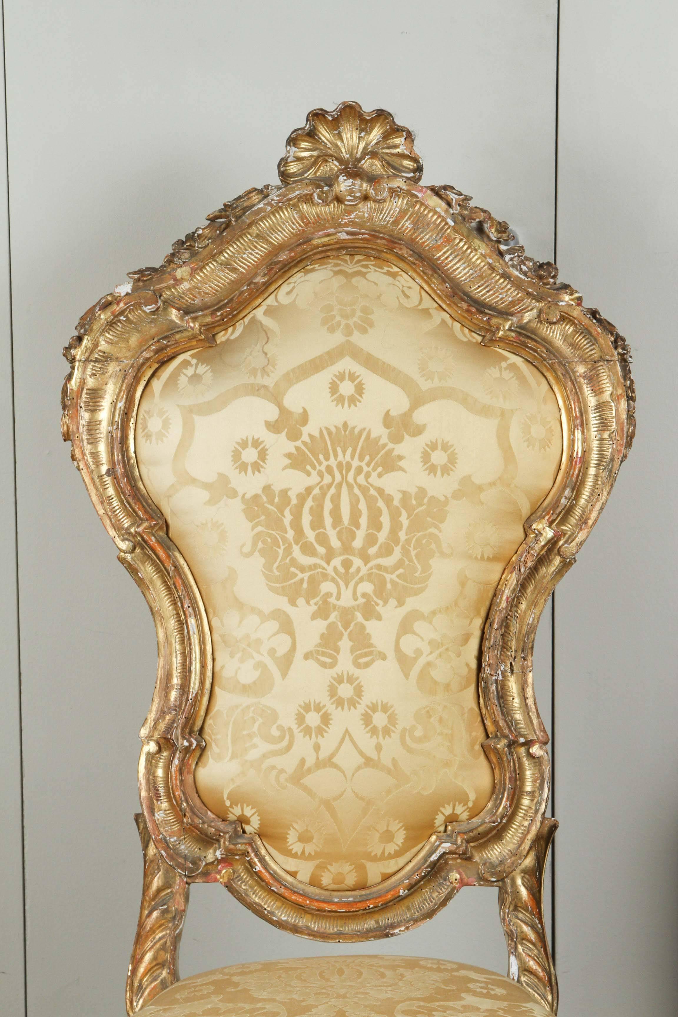 Ornately carved 18th century, French opera chair with gilded finish and upholstered in gold silk damask. 

  