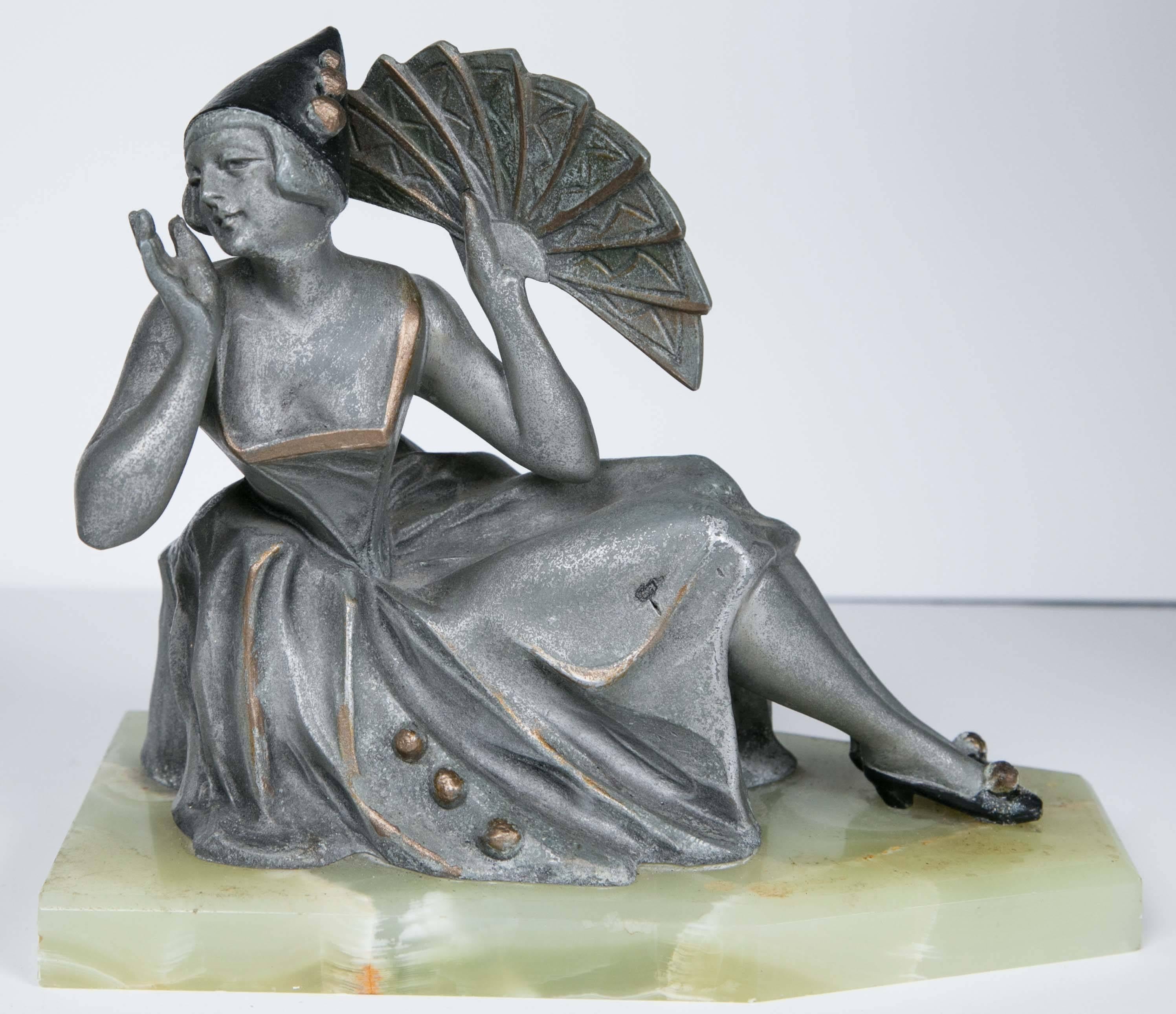 This pair of bookends are mounted on pale green alabaster (one base repaired). Each figure seat with bent knees. The female holds a fan aloft. The make wears a frilled gold collar. Each with gold 