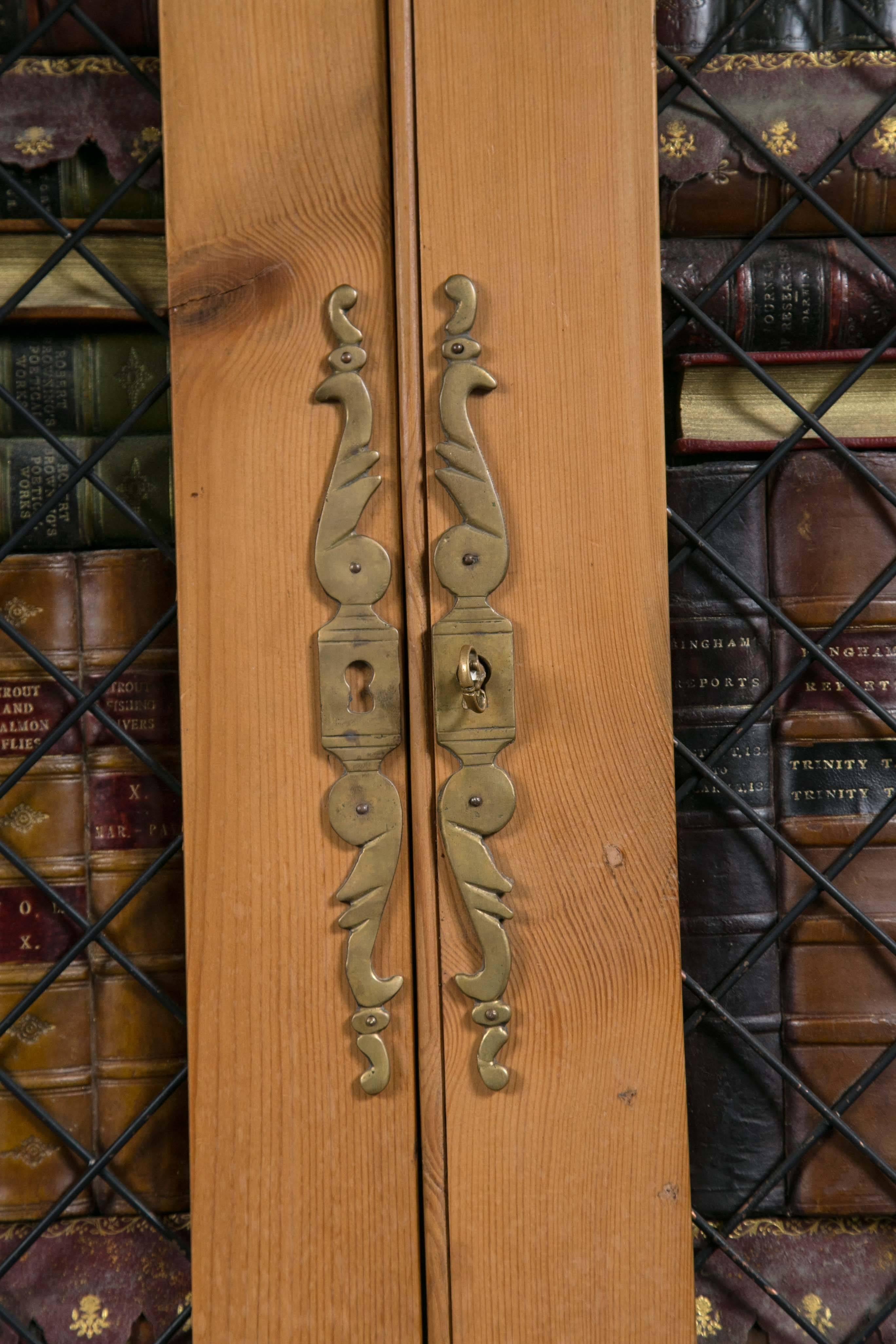 Removed from a cabinet, these doors are made of pine with brass grill work.
Behind the grill work are dozens of book spines resting on 