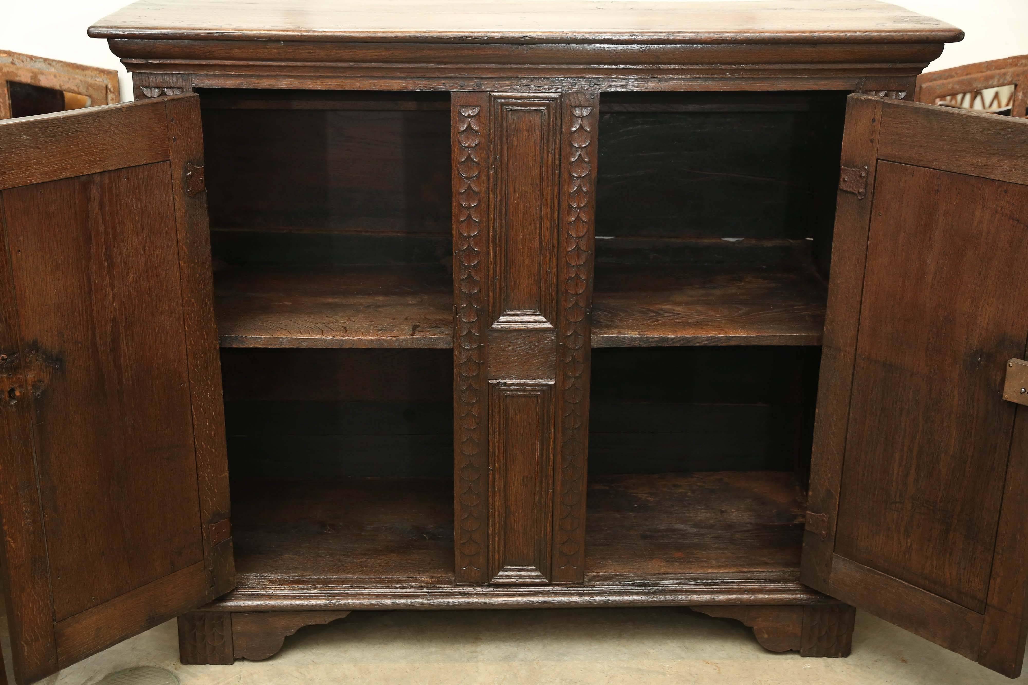 17th century oak cabinet with carved vertical detail bordering two doors. Bracket feet.