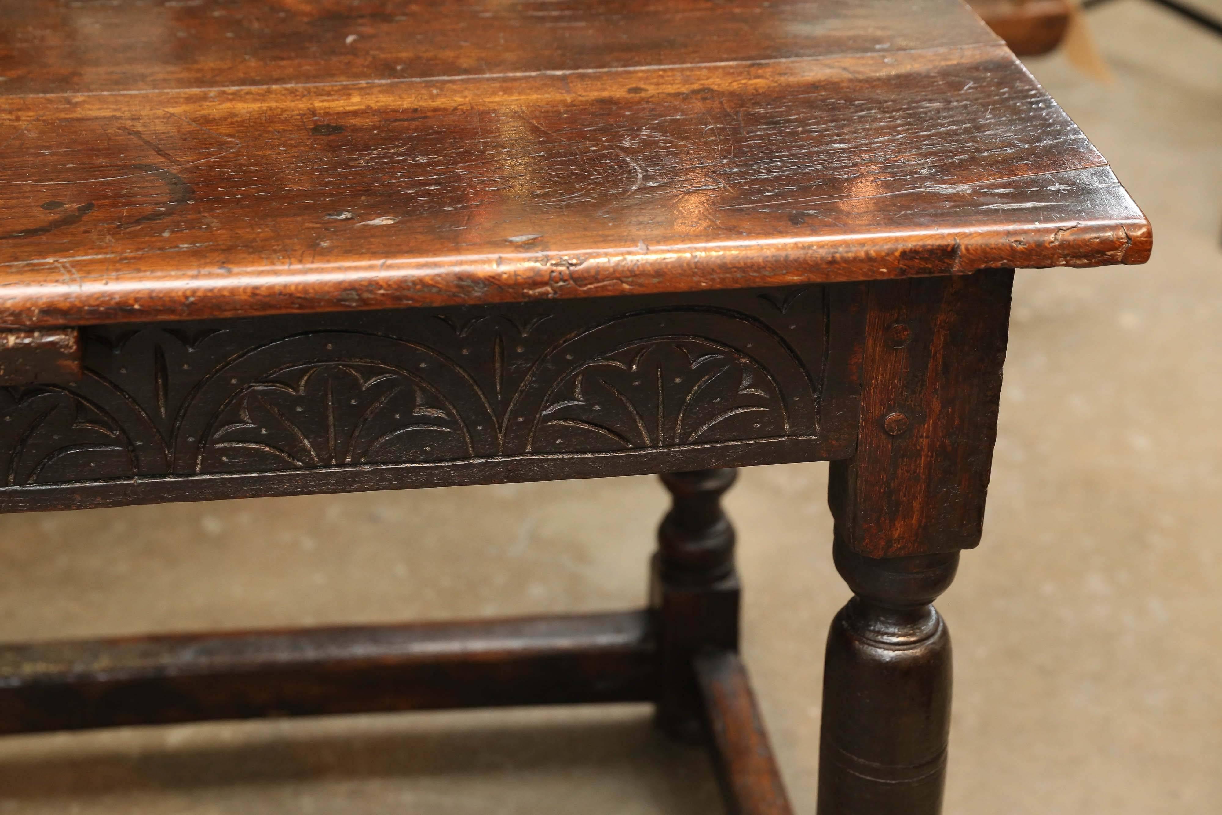 Antique 17th century Irish oak table with carving on the apron on three side. Turned baluster legs with beautifully worn stretchers, all original to the piece, between the legs. Legs then end on flat bun feet. Beautiful patina and worn edges on all