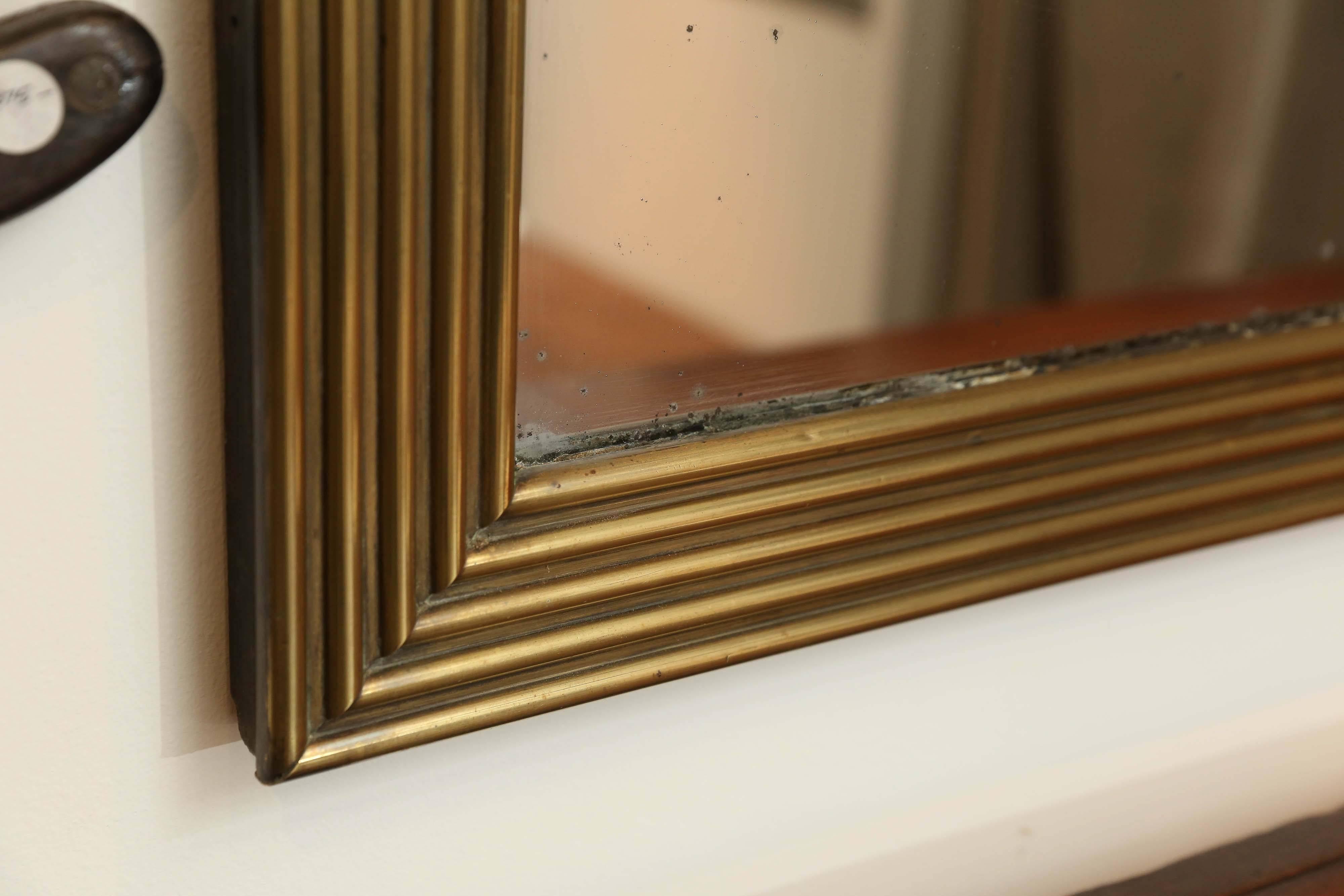19th century brass mirror often found in French Bistros that wanted a more economical alternative to gilt mirrors. Beautiful craftsmanship of the layers and layers of brass that were used to make this raised reeded design. The brass has been cleaned