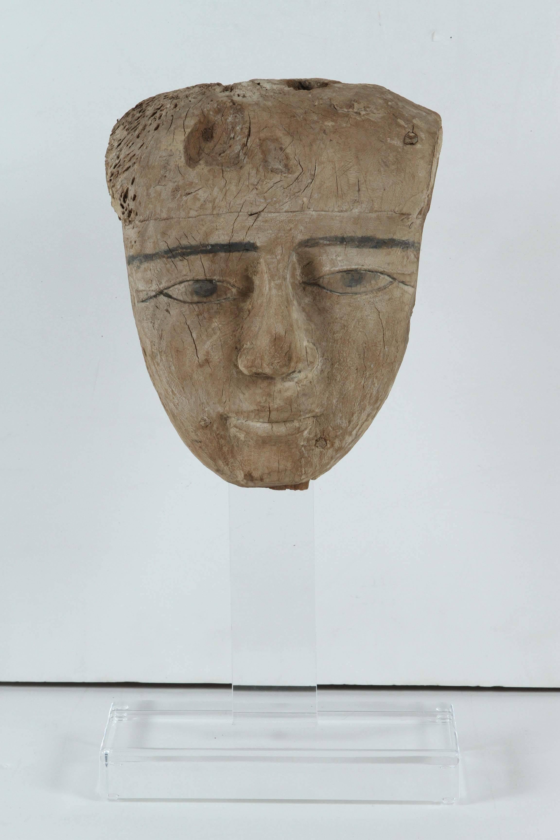 Large, carved cedar wood burial mask with paint traces on a custom, Lucite stand.