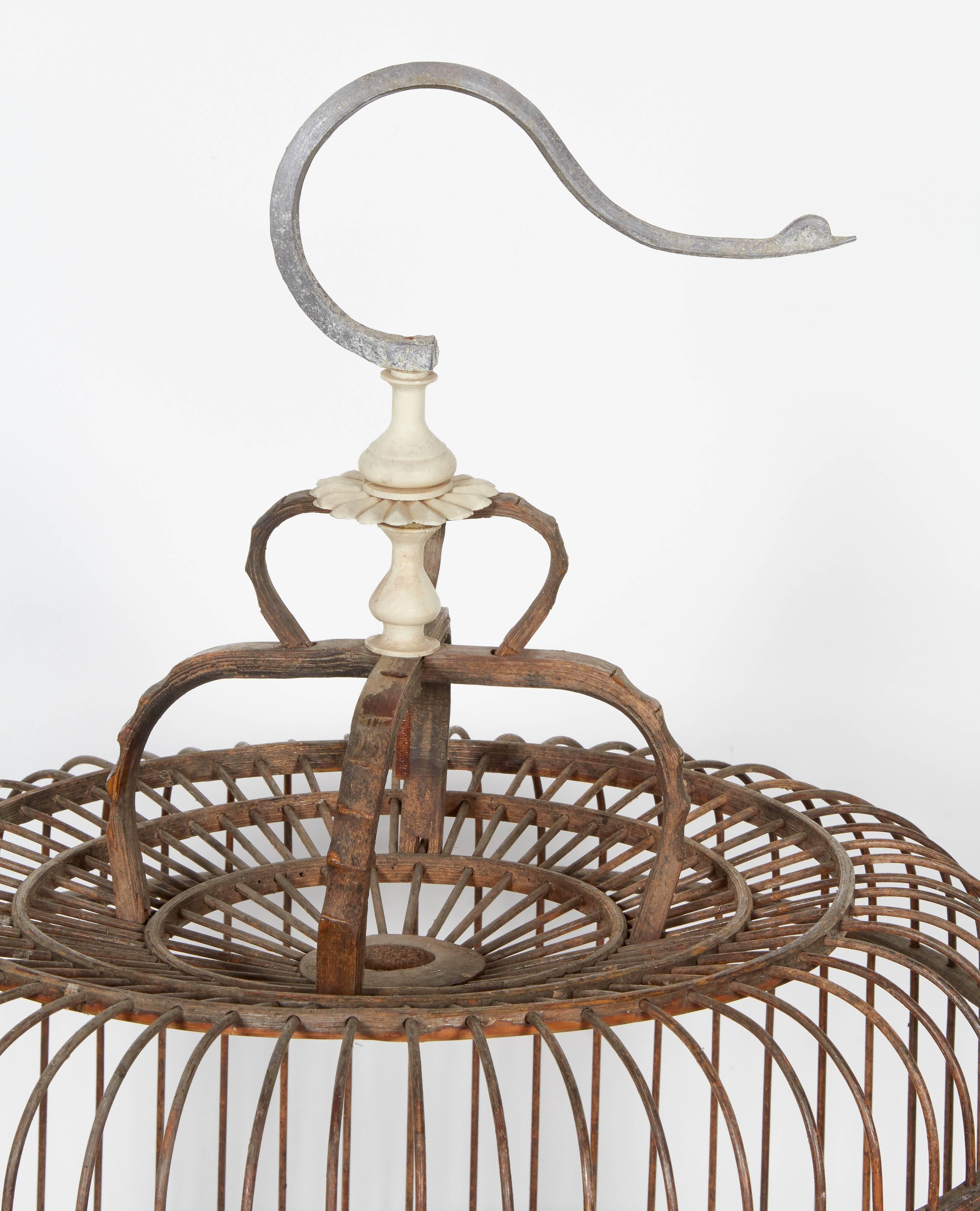 A painstakingly constructed vintage Chinese birdcage with a graceful bird shaped hanger. Classic form. Beautifully worn throughout with a very weathered base and a small porcelain feeding bowl. From Shandong Province, circa 1940.
M910a.