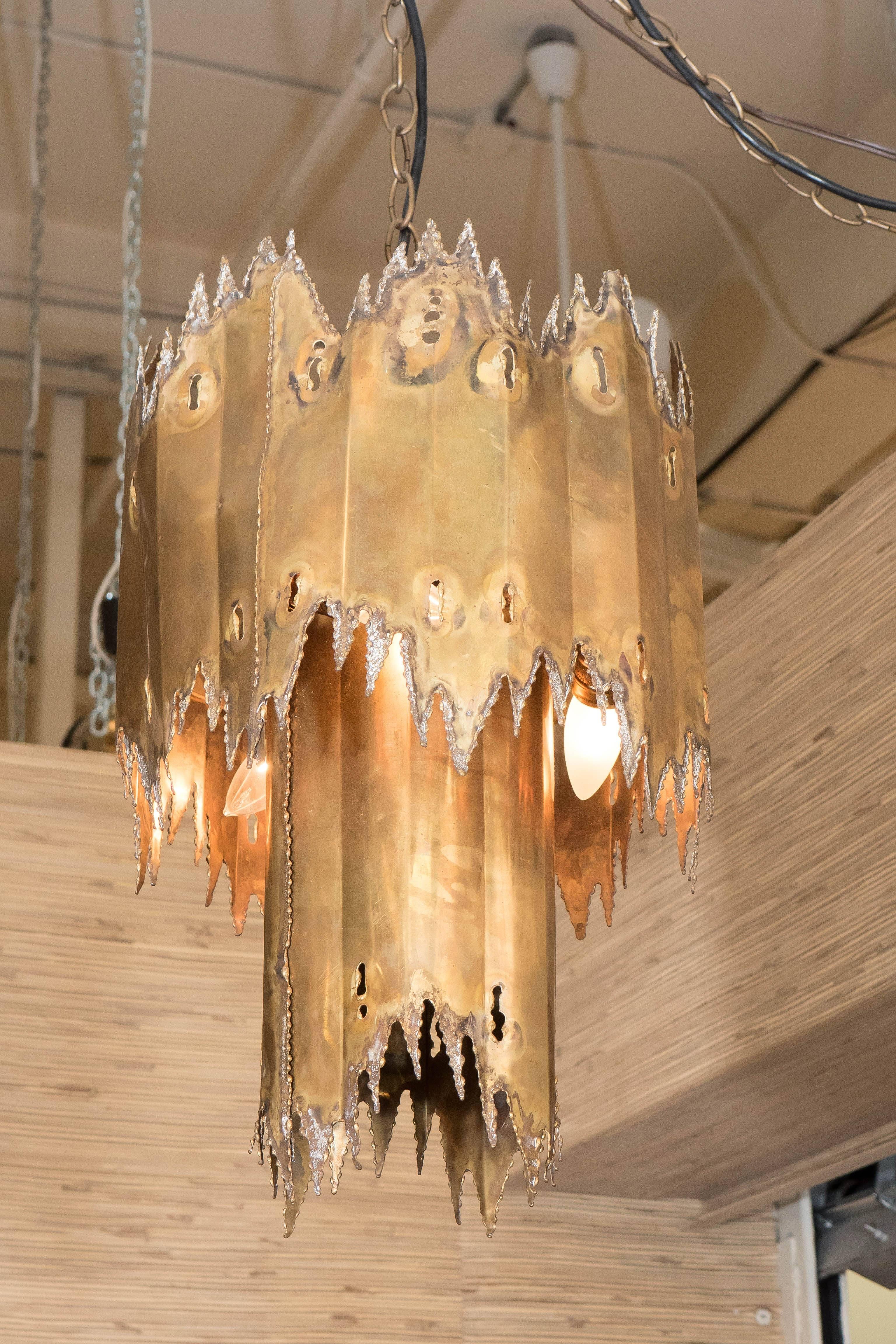 A contemporary chandelier in the Brutalist style, composed of two tiers of artfully torched and soldered sheets of metal as shades. Very good condition, consistent with age and prior use.