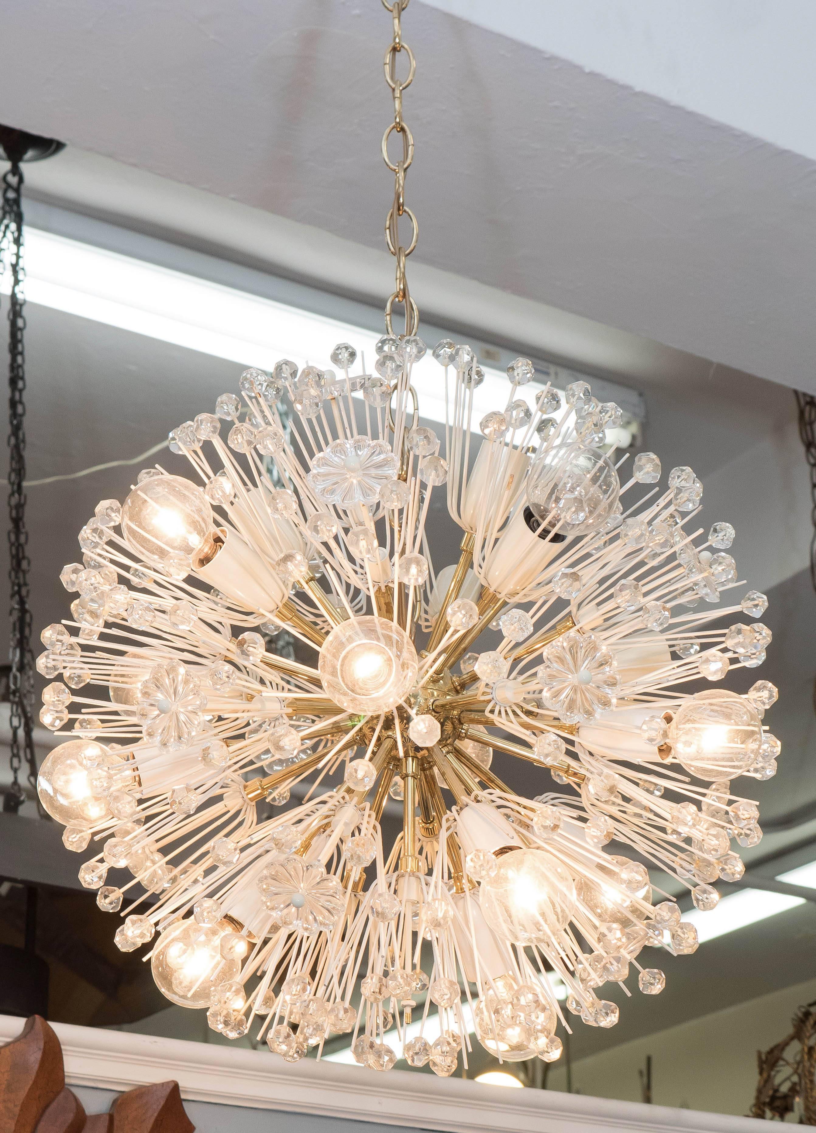 This 'dandelion' Sputnik chandelier by Austrian designer Emil Stejnar and produced by Rupert Nikoll circa 1960s, includes bright brass nucleus and arms, with white enameled socket covers, and surrounding faceted glass beads and rosettes. Very good