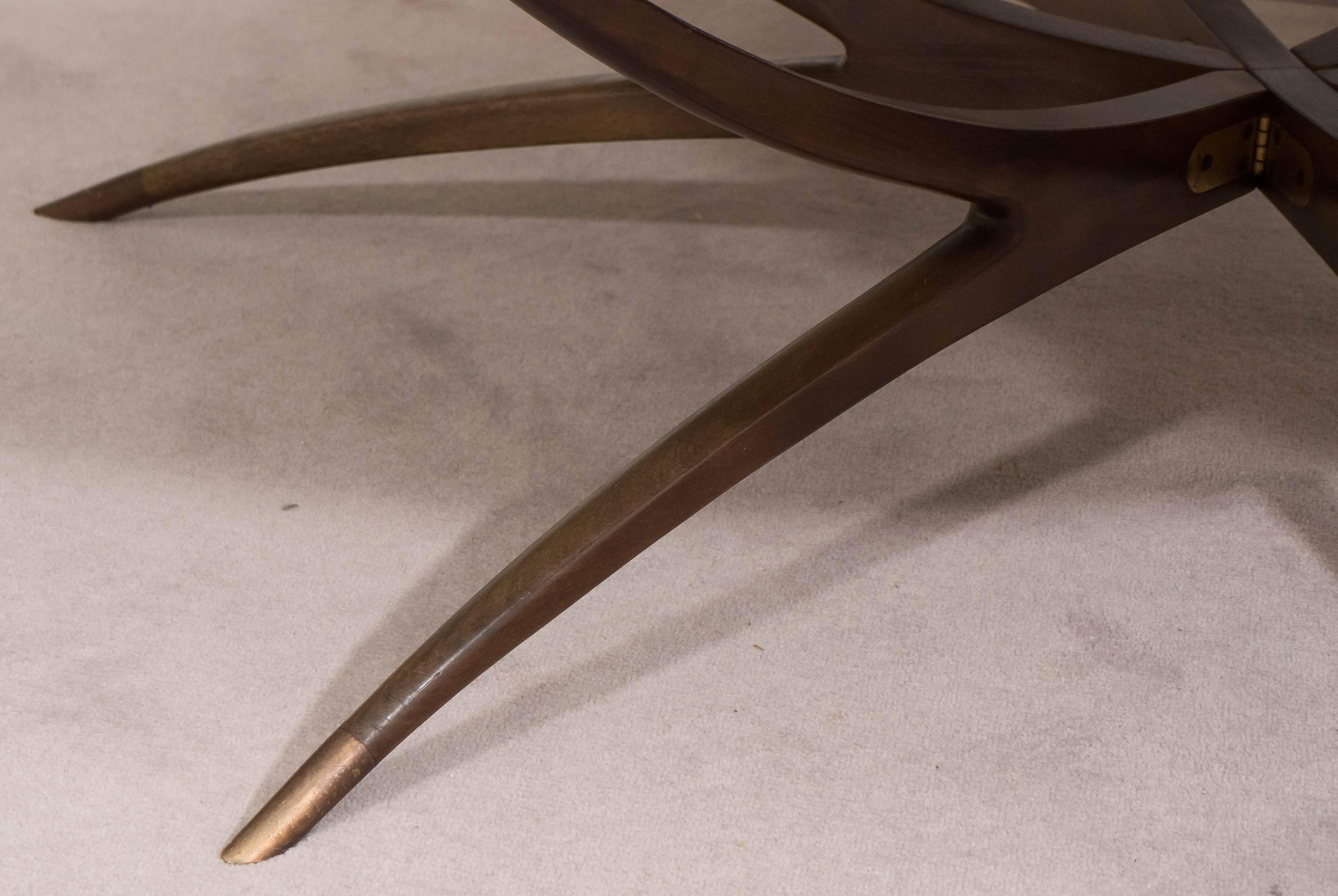 A coffee and cocktail table, produced late 1950s-early 1960s, with milk glass top, inset against a walnut frame, on elaborate spider leg base with brass sabots. This table remains in very good vintage condition, consistent with age and use.