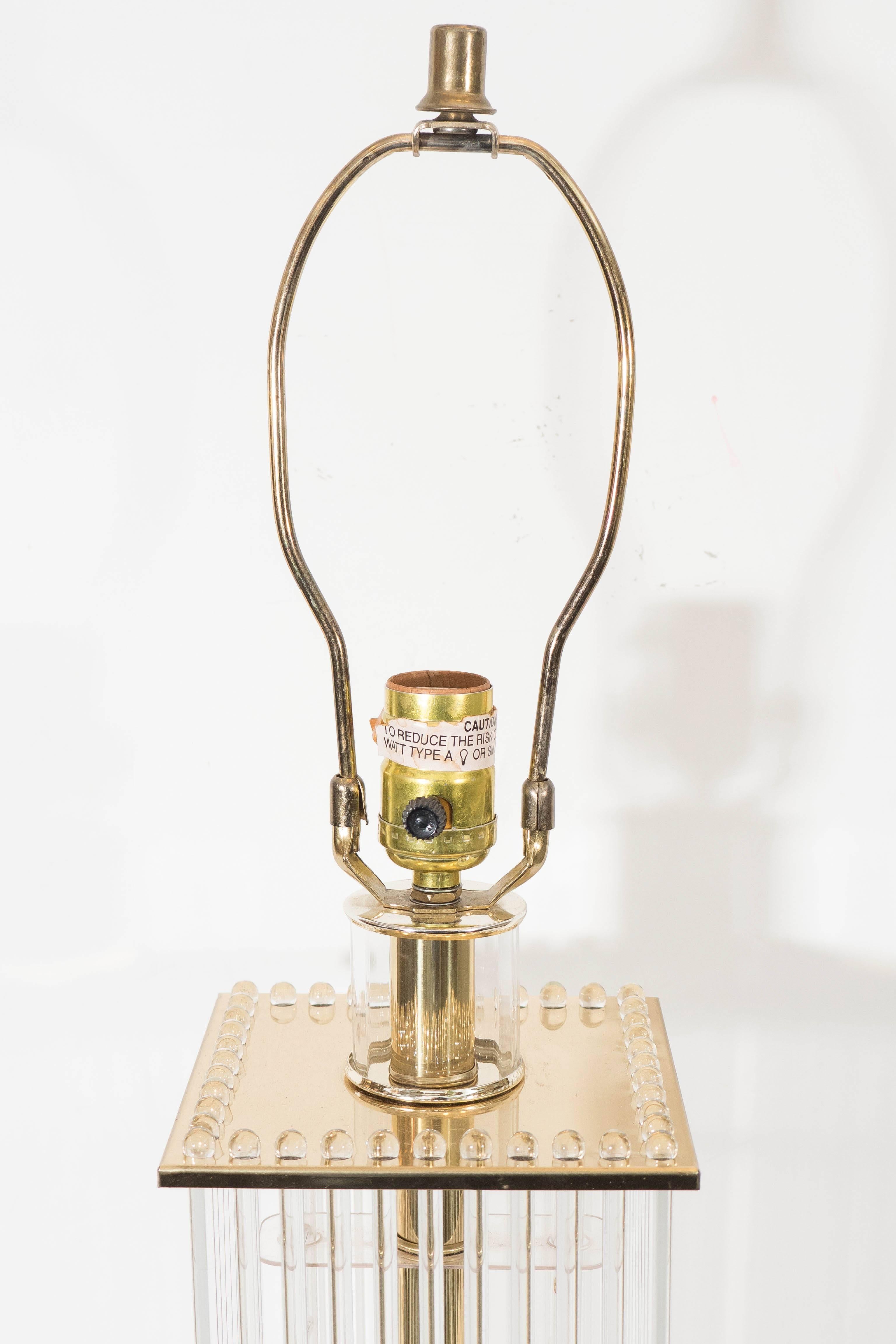 This vintage table lamp by Gaetano Sciolari, produced circa 1970s, comes in polished brass, with single socket on lengthy stem and square brass plates, hanging glass rods suspended to the top, two sockets to the bottom, elevated on square base.