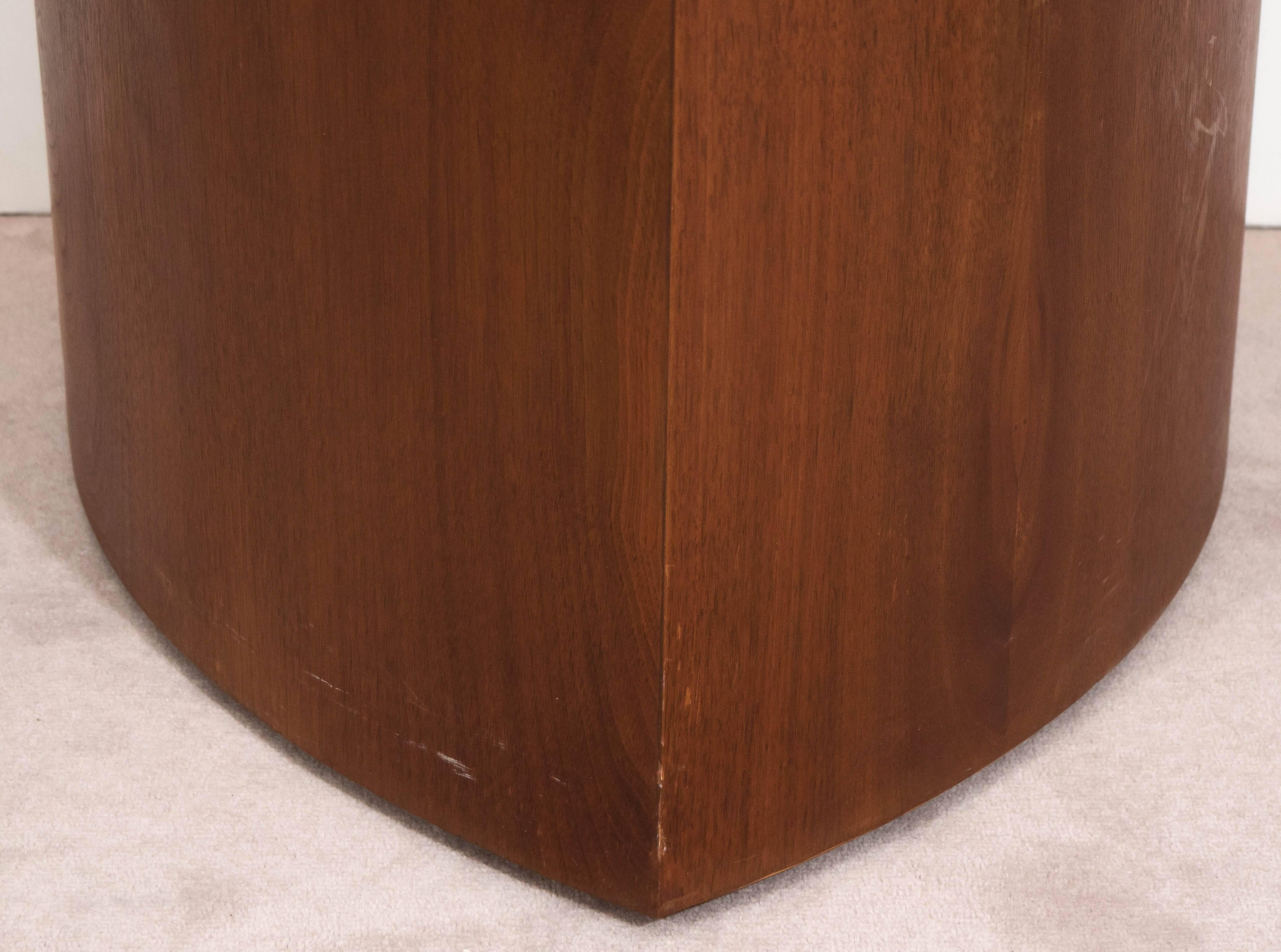 Cette table d'appoint, produite vers les années 1960, comprend un plateau triangulaire en travertin italien, sur une base cunéiforme en noyer, le plateau se détachant de la base. La table reste en très bon état, avec une présence mineure d'usure et