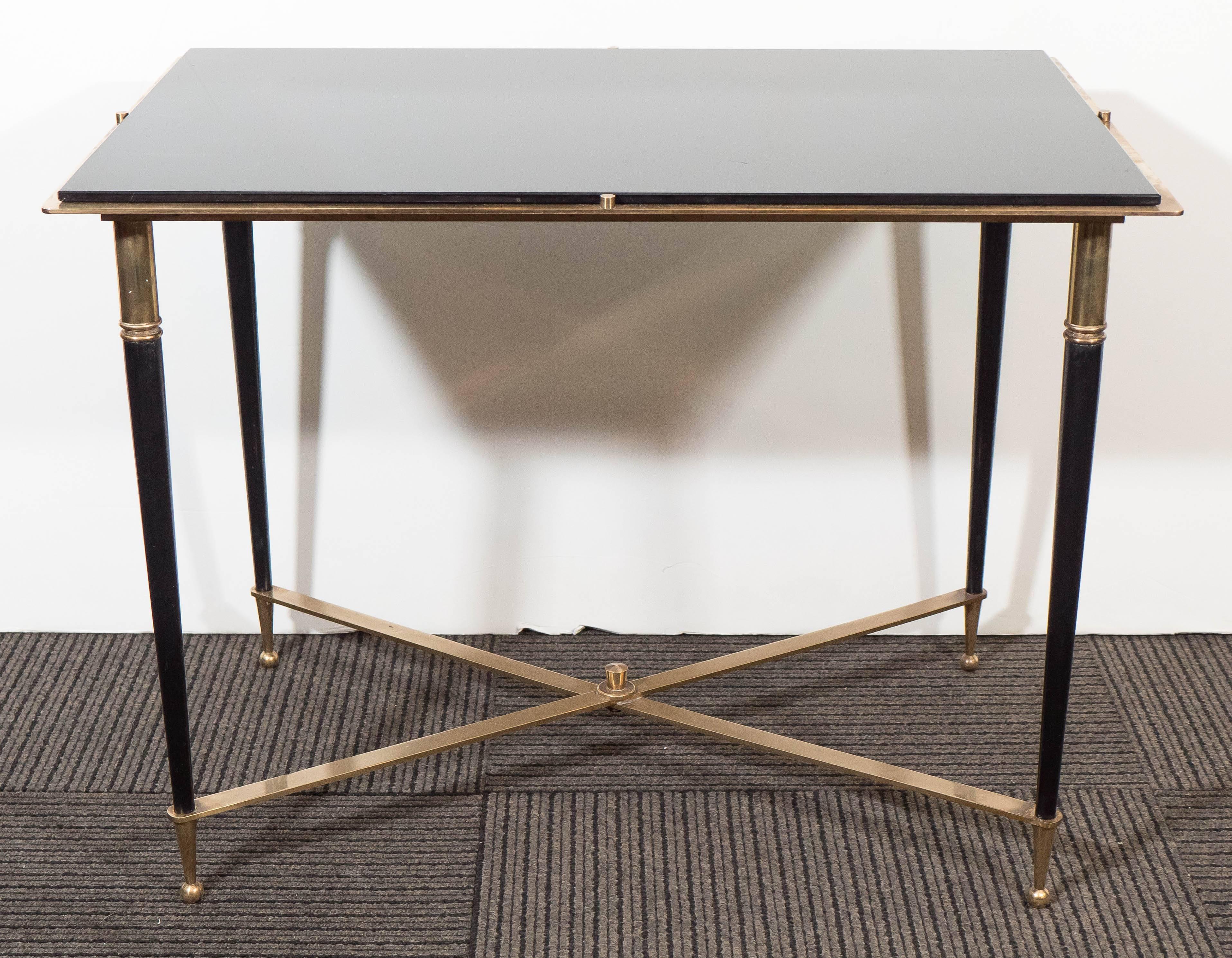 A side table designed in the style of Maison Jansen, produced in France, circa 1960s, with black glass top on bronze frame, over tapered legs with ball feet and X-form stretcher. The table is in very good vintage condition, consistent with age and