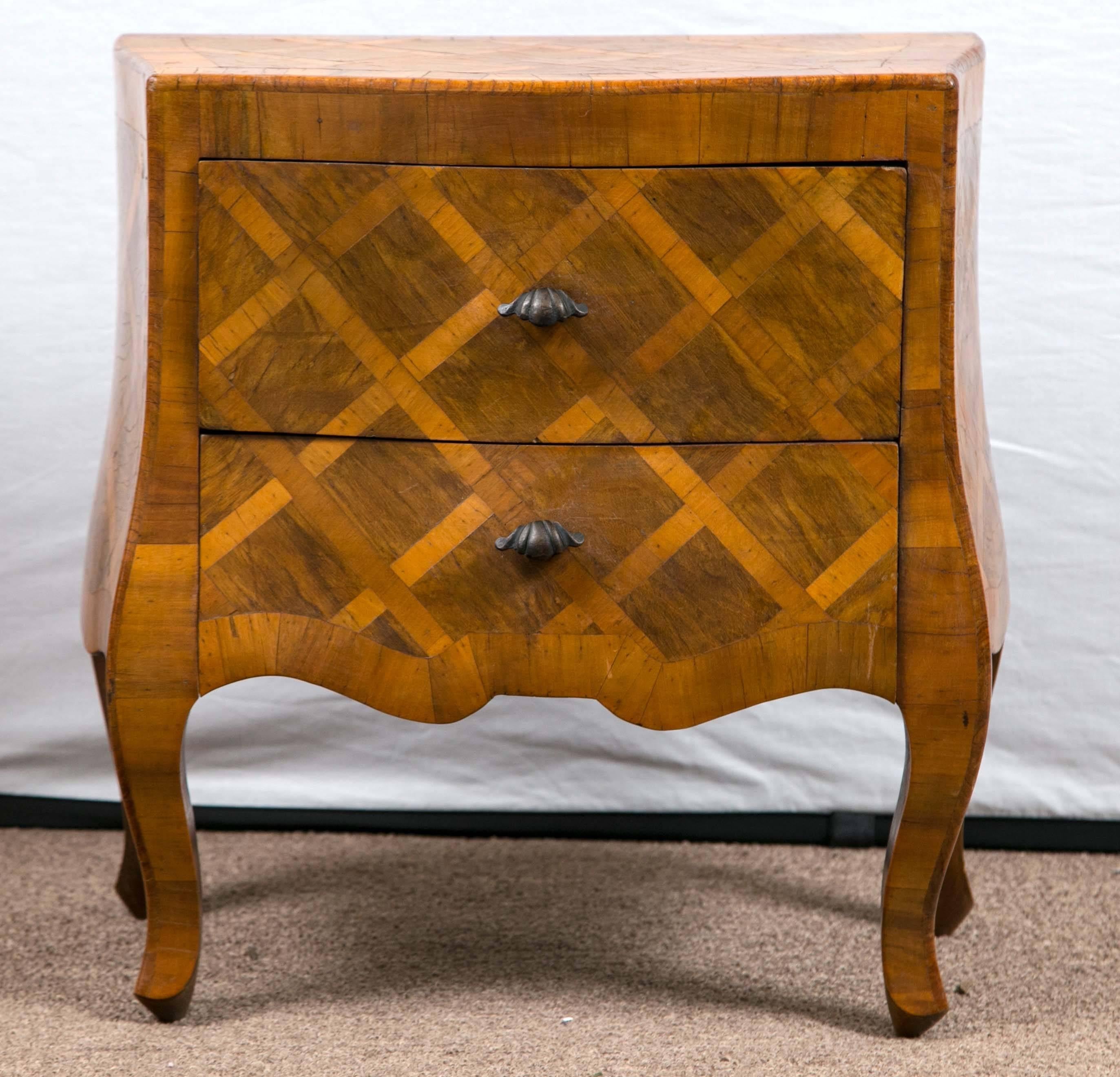 The shaped rectangular top with a bombe case fitted with two long drawers on cabriole legs, the whole inlaid with lattice work marquetry.