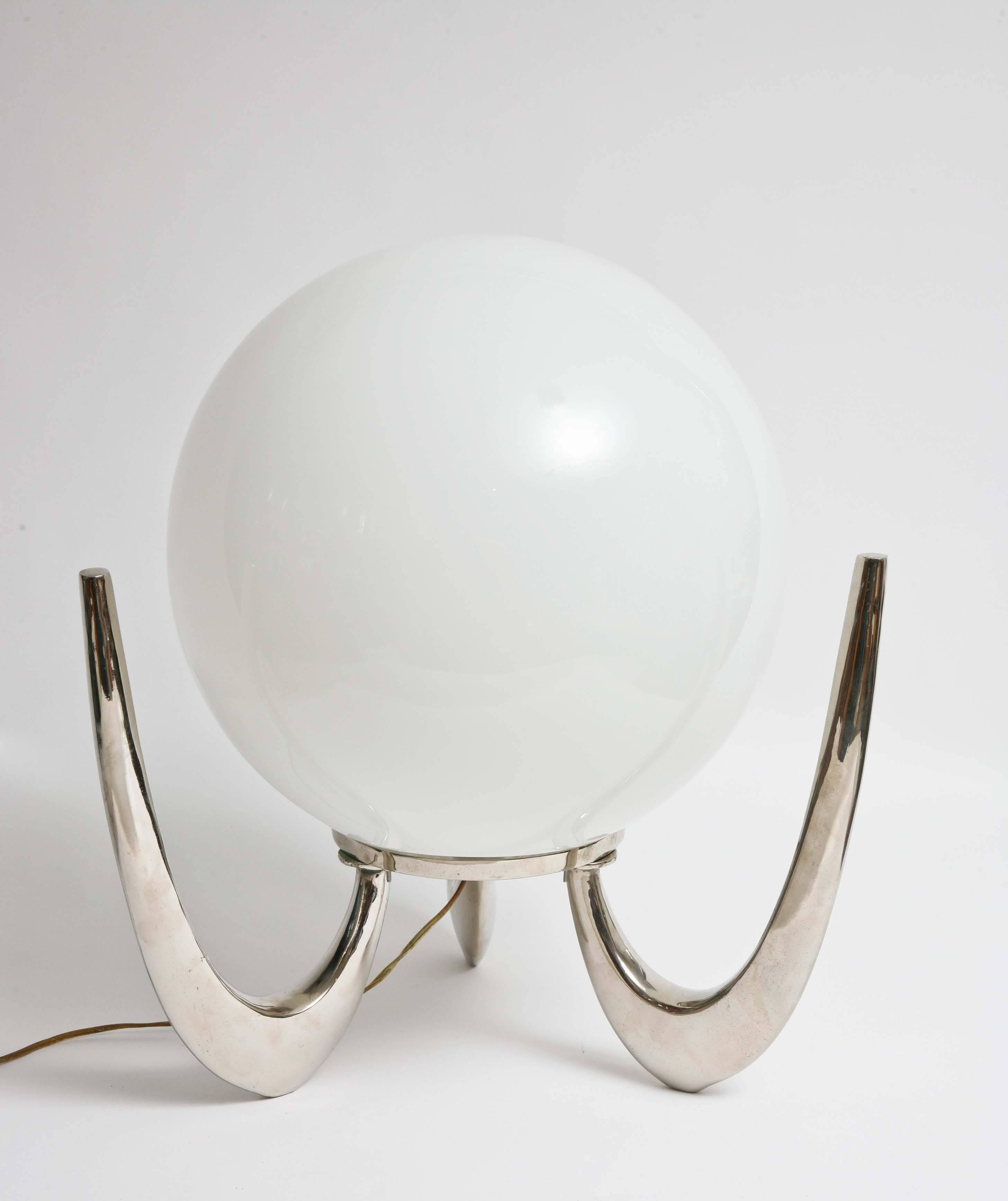 Metal frame plated fin. Large shiny glass orb center which conceals lighting mechanism. Three boomerang like supports act as legs. Very futuristic looking light fixture. Wiring is in working order and lamp is in very original condition.