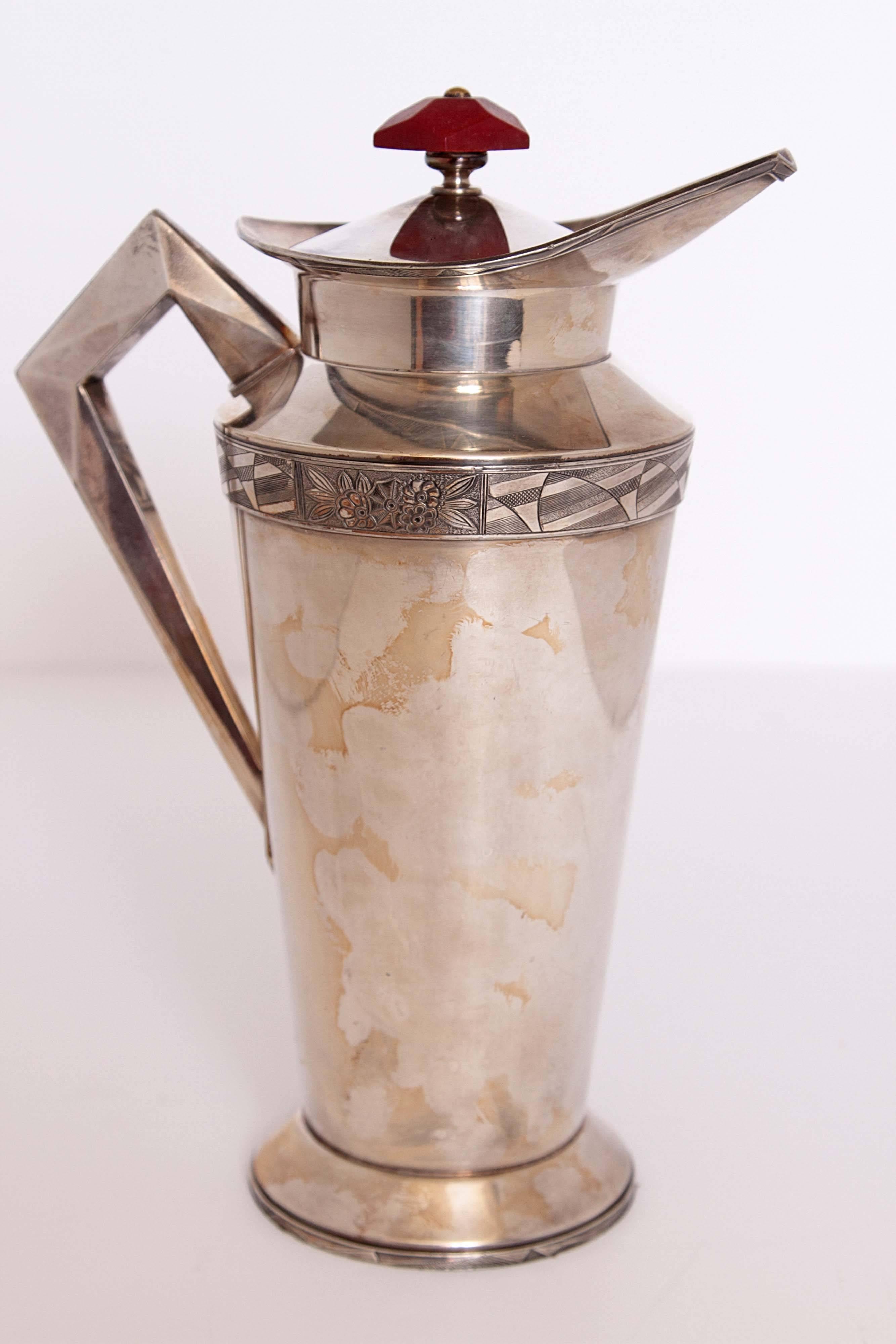 Great modernist form with cubist handle, etched detailing top and bottom, red bakelite or other phenolic finial.
Original cork cap liner intact, with integral strainer.
Fully signed, Benedict Modernistic form # 563. E.P.N.S. B.M.M,
circa