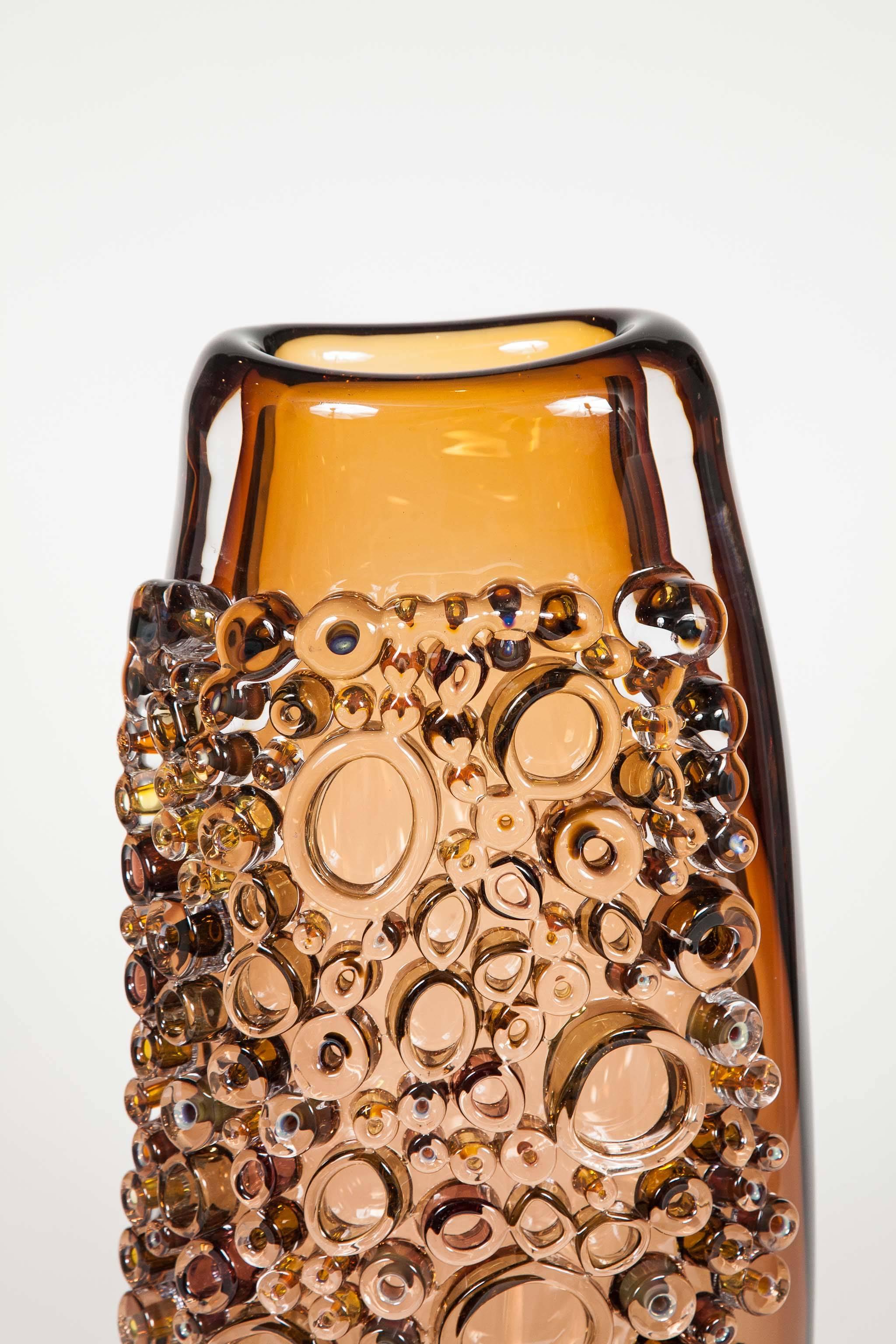 Tube Field Amber, High Shape II is a unique handblown and crafted glass vase & artwork by the German artist, Sabine Lintzen. The initial inner form is free-blown and adorned with various individually shaped murrini, all created in the same sublime