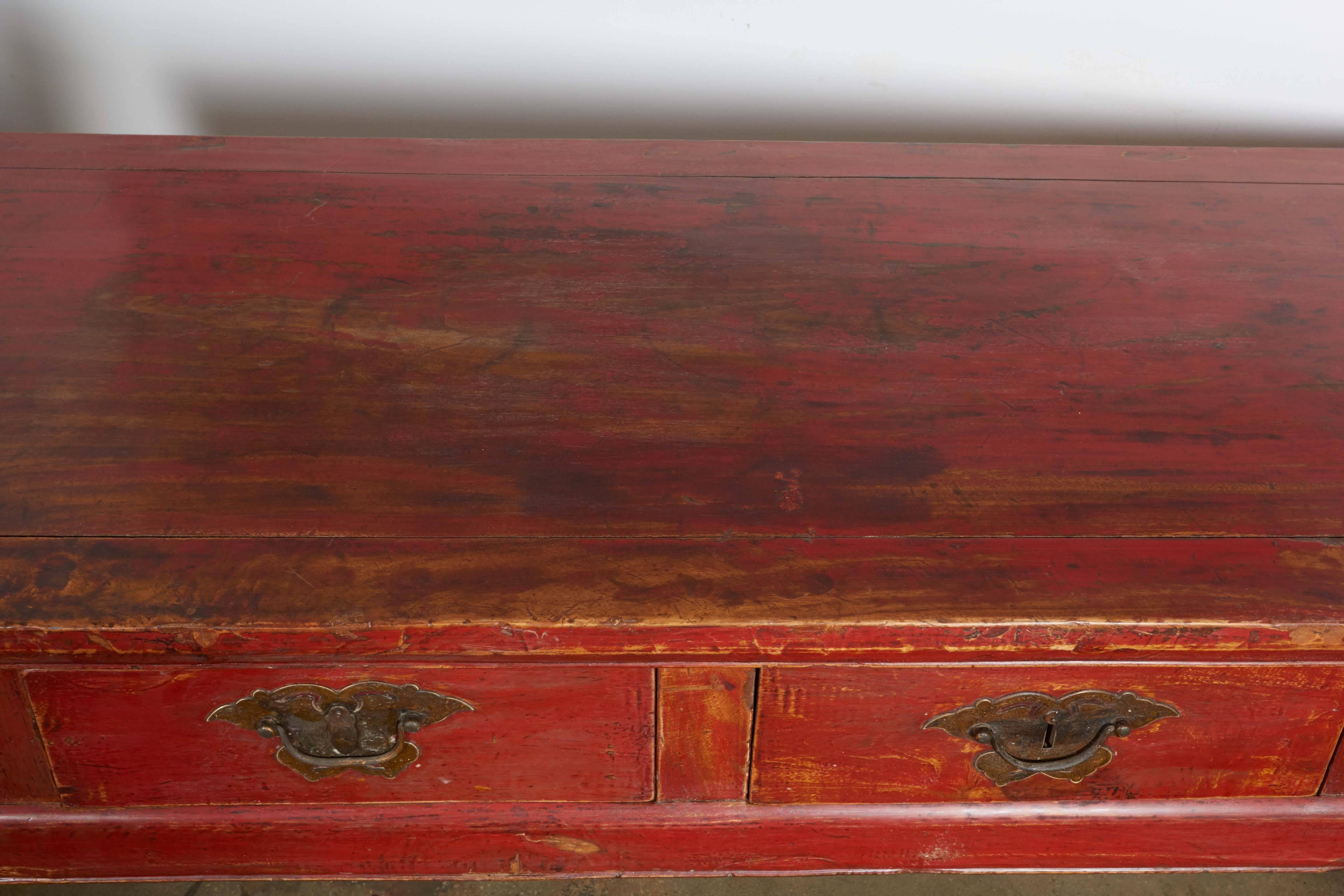 A red lacquered four-drawer scholar's desk, original hardware, peach wood, Zheklang.
