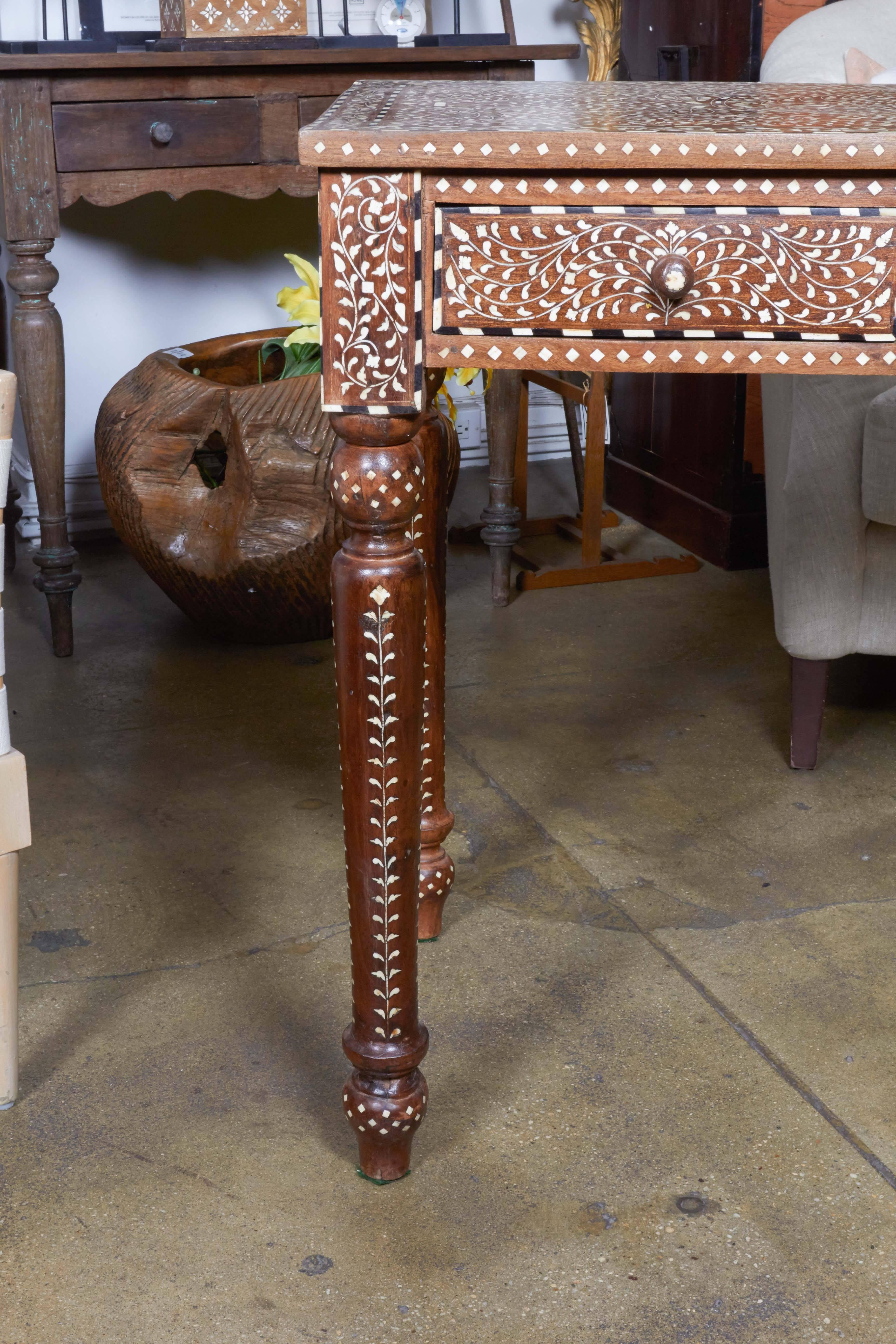 A wood desk with two drawers, turned legs and bone inlay in a Classic pattern on all sides, from India.