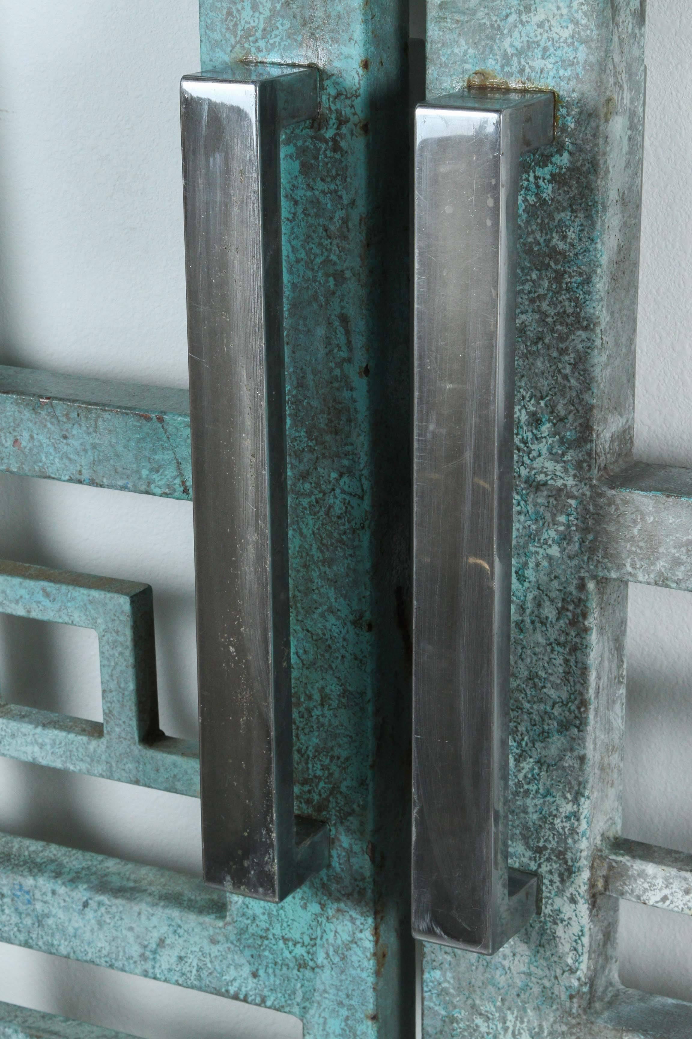 Spectacular pair of large heavy steel architectural gates with a geometric design
from a Palm Springs CA retail space. 
They have a wonderful verdigris finish and large chrome handles.