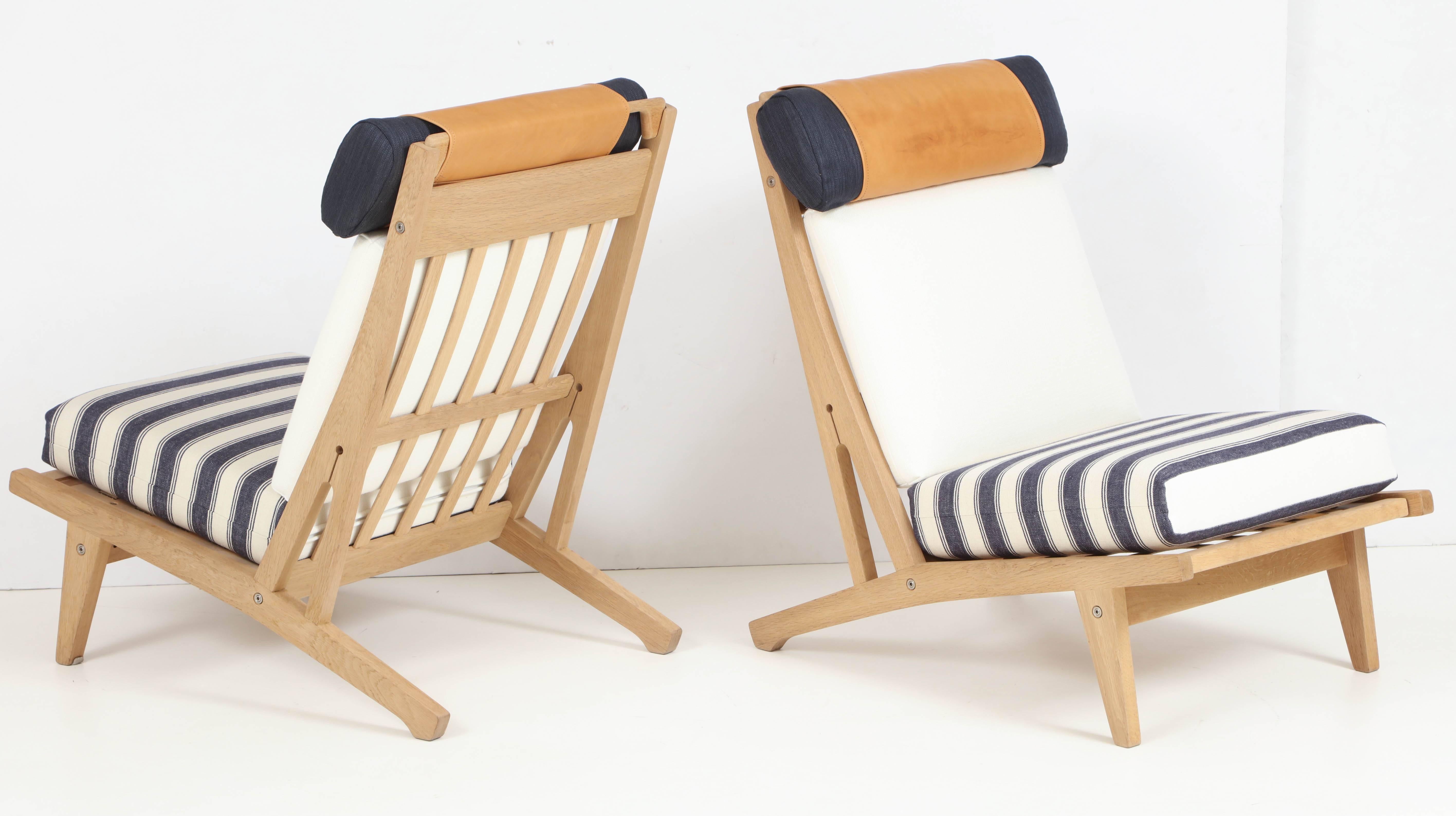 Pair of Hans J Wegner Getama lounge chairs made of oak and reupholstered in  Rogers & Goffigon linen fabric, denim and leather. The chairs are each signed with branded manufacturer's mark to underside 
