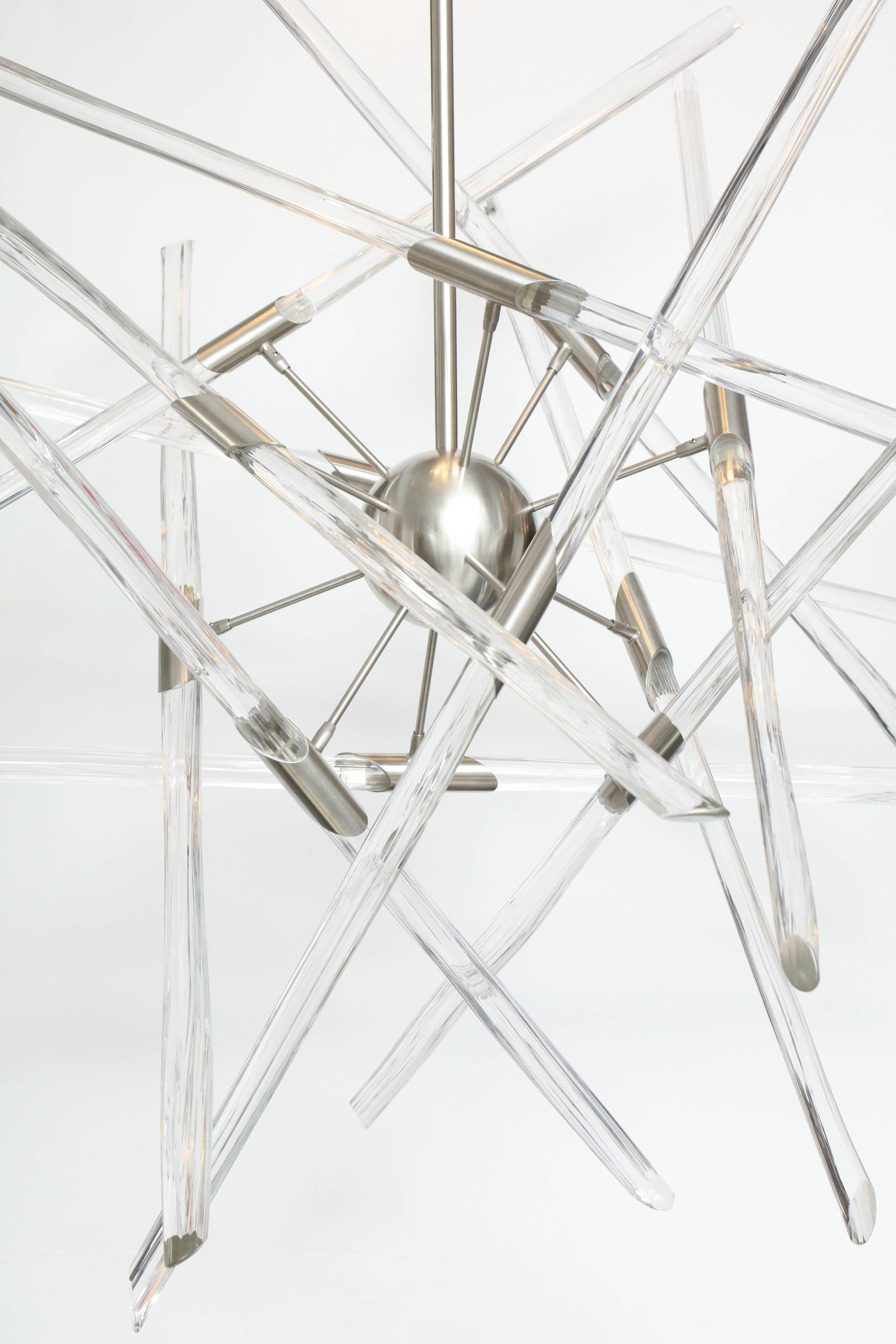 Contemporary American artist Barry Entner's Tangent Chandelier is comprised of clear textured solid glass sticks and a nickel plated steel frame. The canopy holds 5 LED round lights that shine down on the adjustable sticks as they orbit a 5