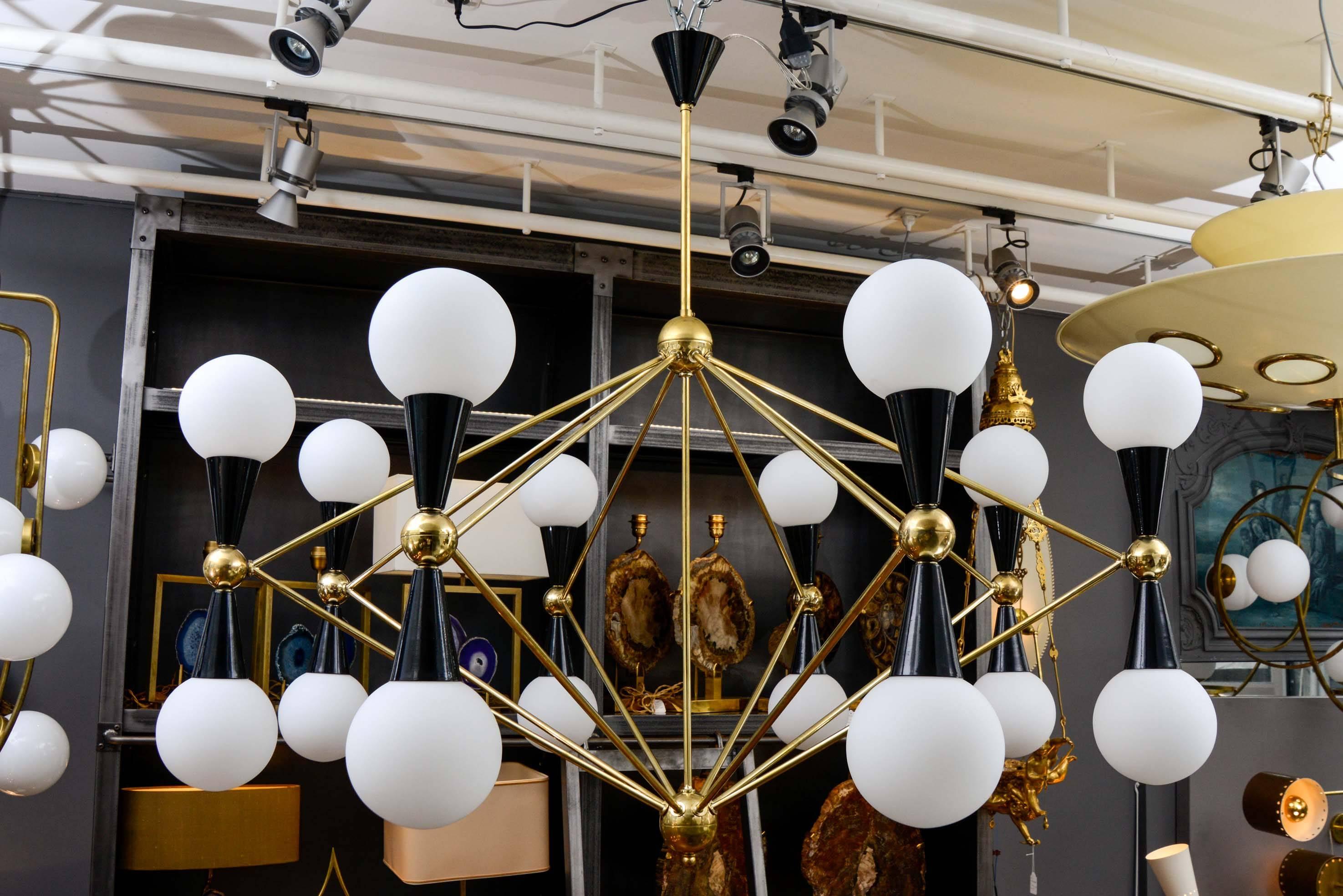 Pair of large brass chandeliers with black enameled metal cones and opaline glass globes holding the lights.