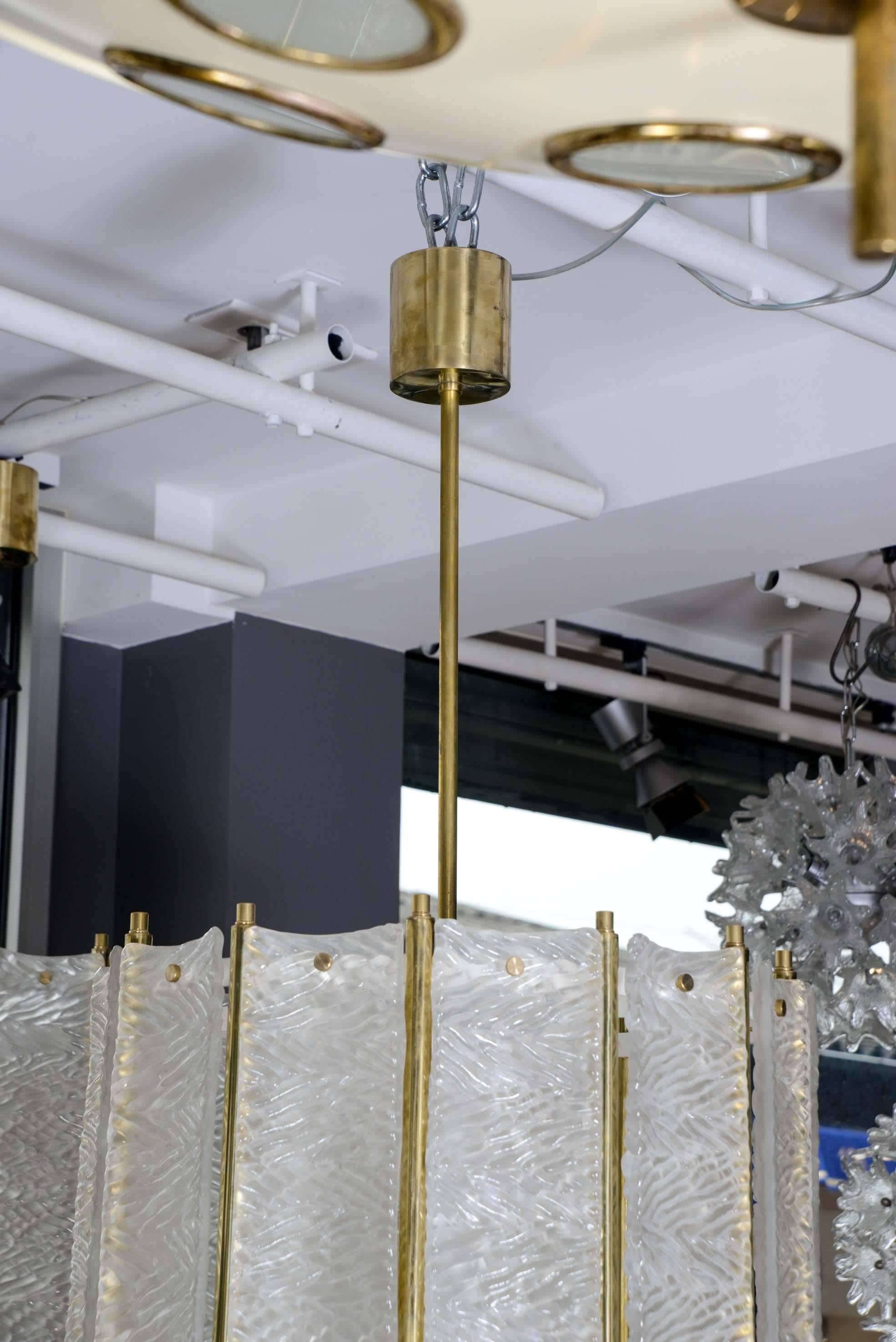 Pair of lanterns made of brass structures and side panels made of textured and opaque Murano glass.